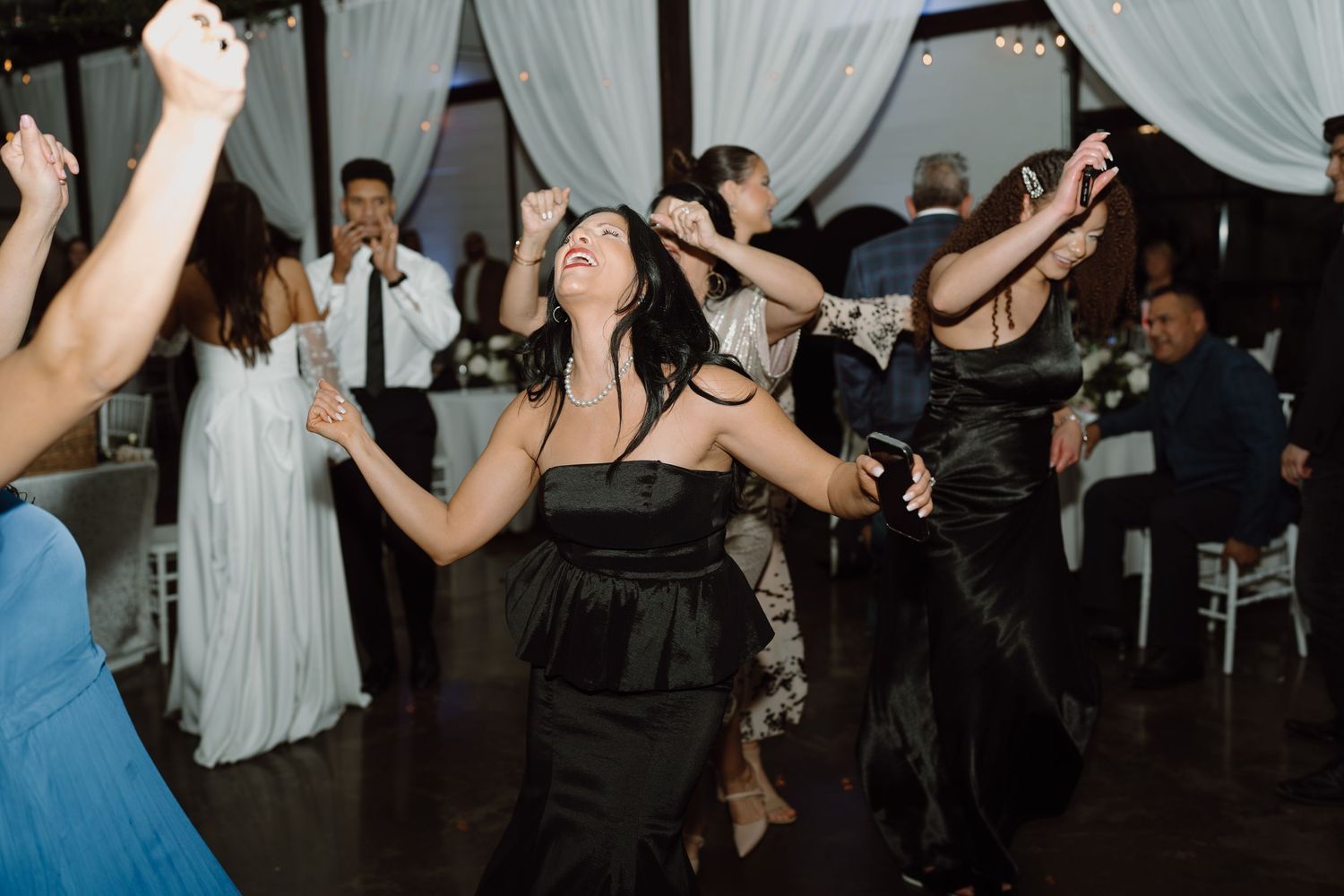 Wedding reception dance floor filled with celebrating guests in formal attire.