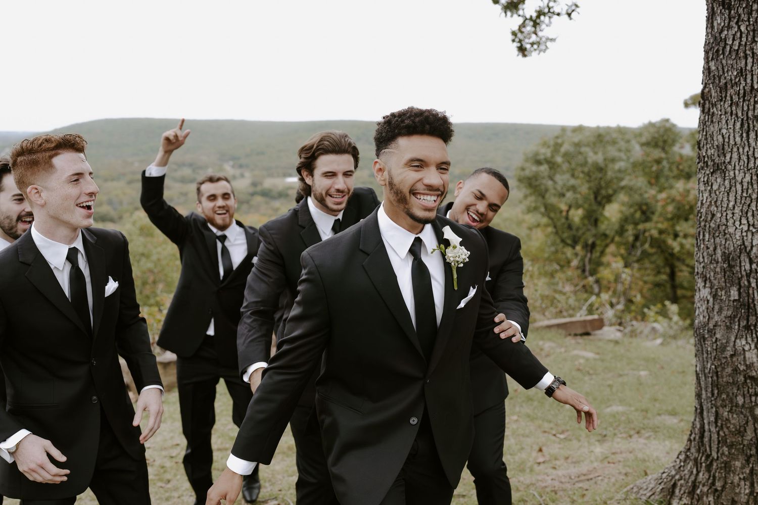 Groomsmen share candid laughing moments during outdoor wedding photography session.
