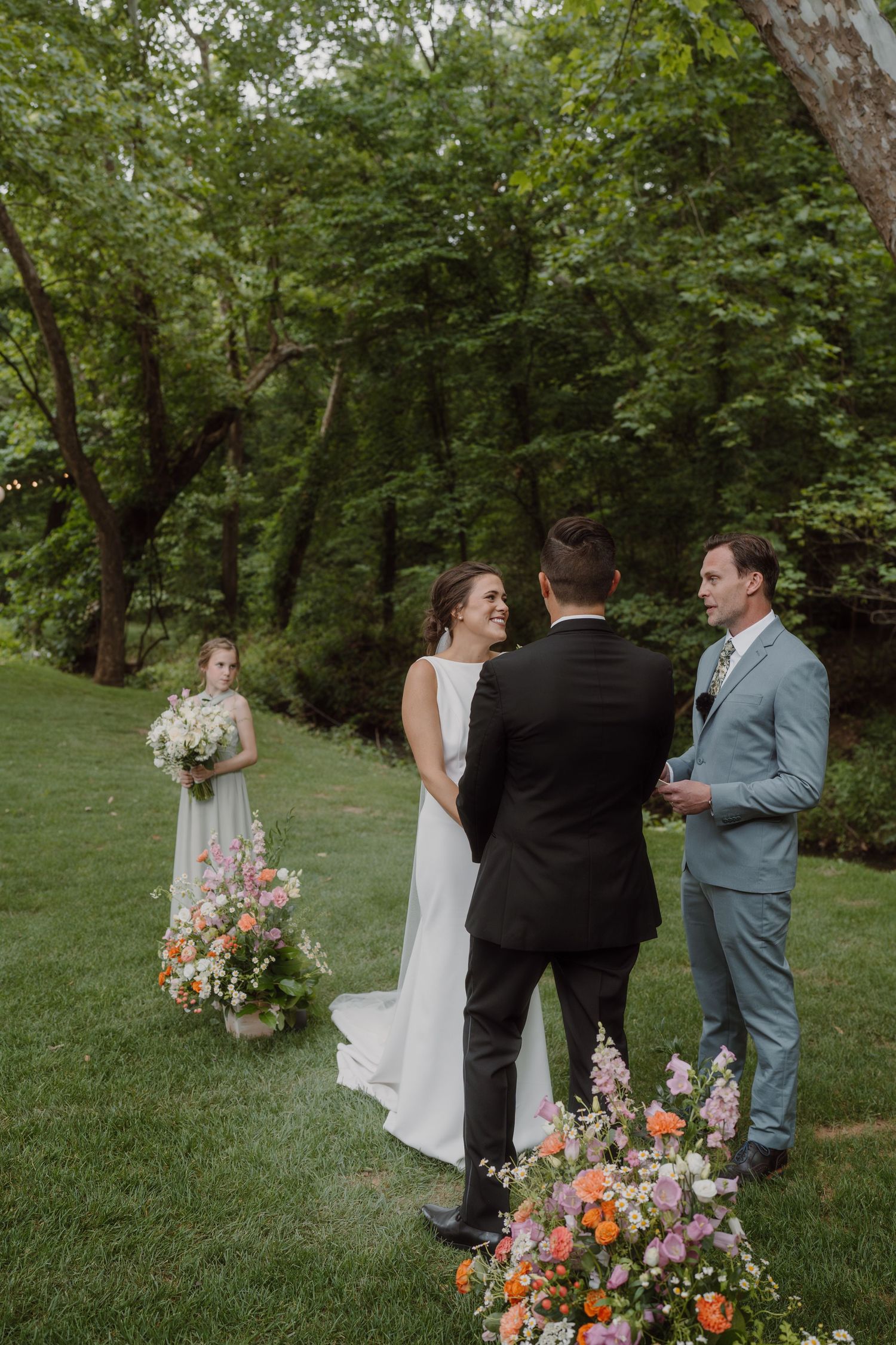 An intimate wedding ceremony moment unfolds in a serene garden setting with bright floral arrangements.