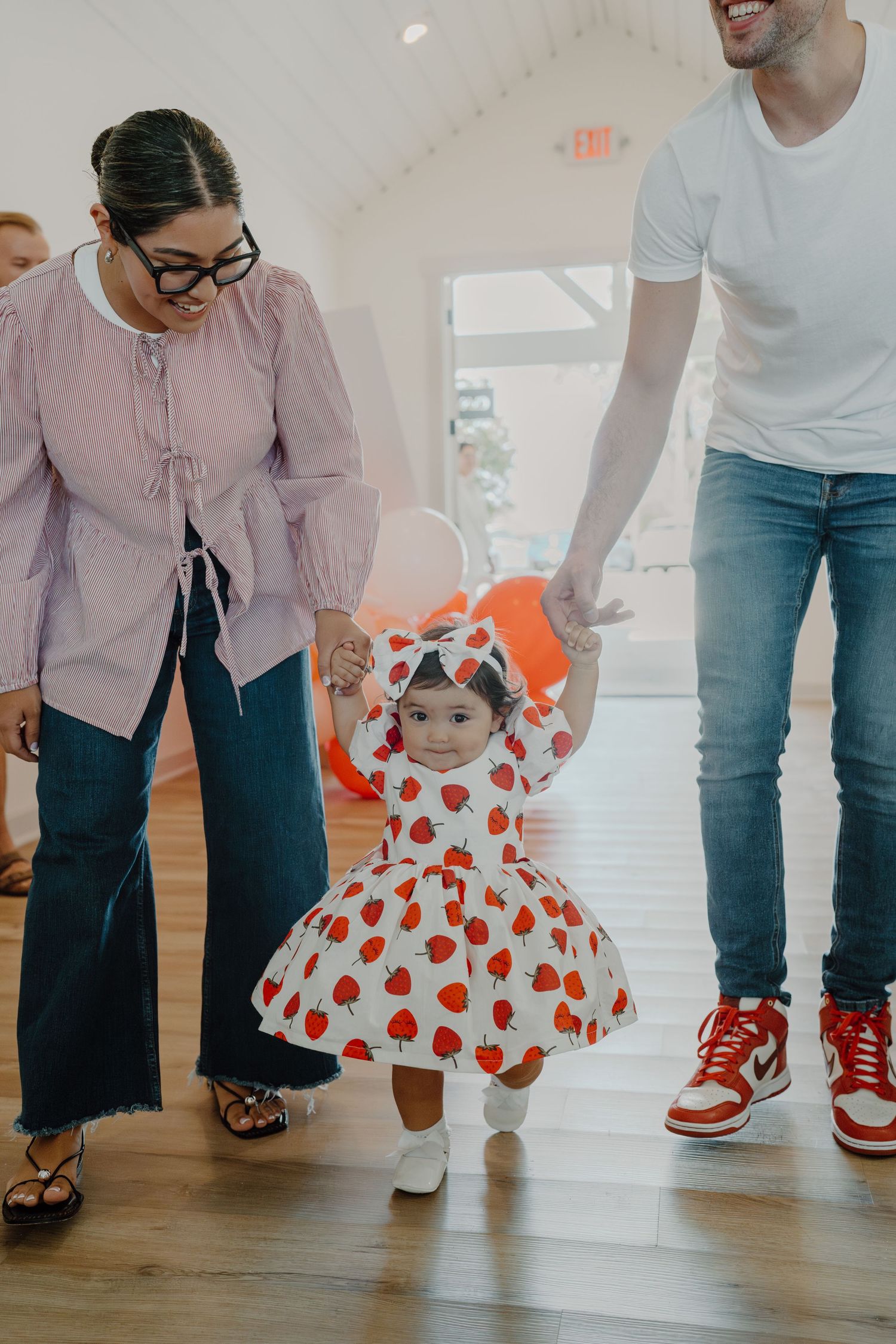 Low angle view of people in casual wear standing on hardwood floors with red and white accents.