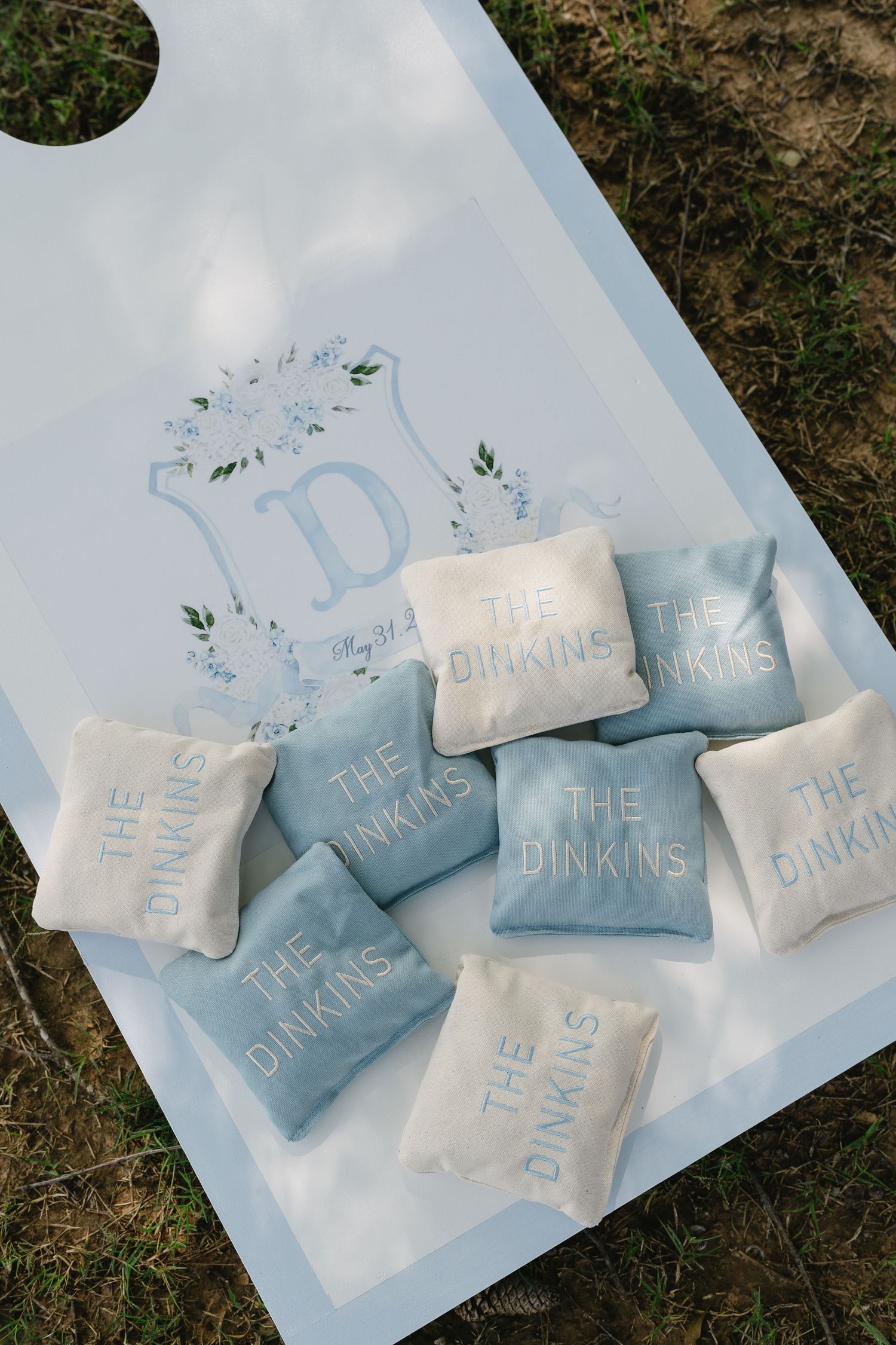 Custom cornhole board with blue and white bean bags monogrammed with The Dinkins wedding crest design.