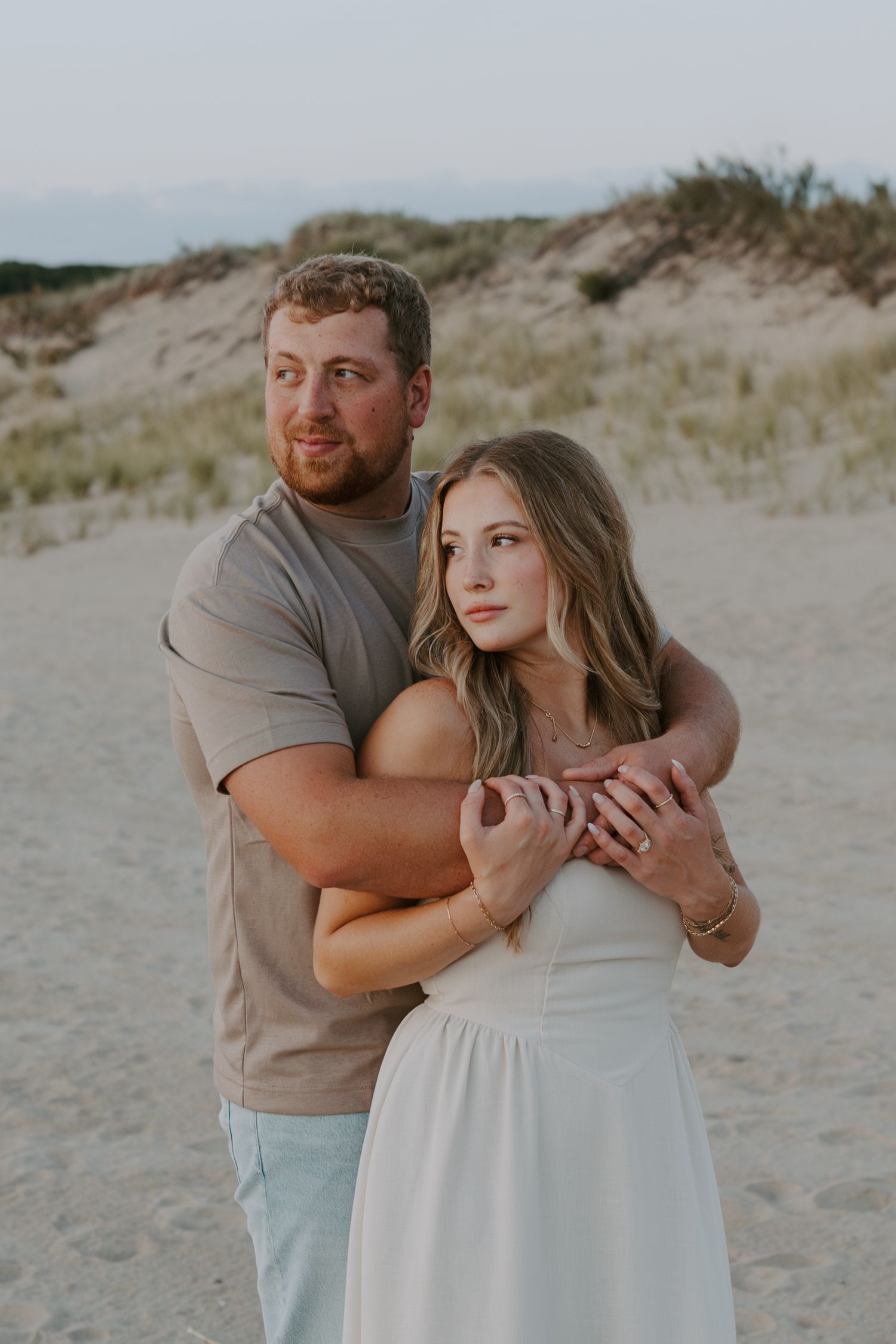 A couple shares tender moments during their beach engagement session near coastal dunes.