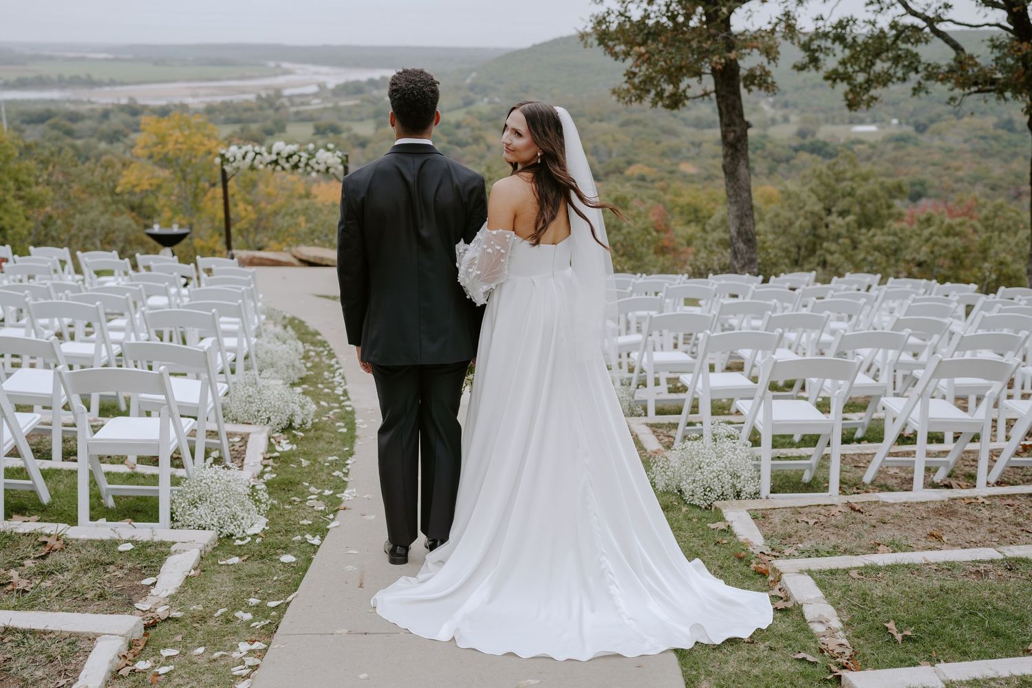 A wedding ceremony site on a hilltop with white chairs and scenic mountain views.