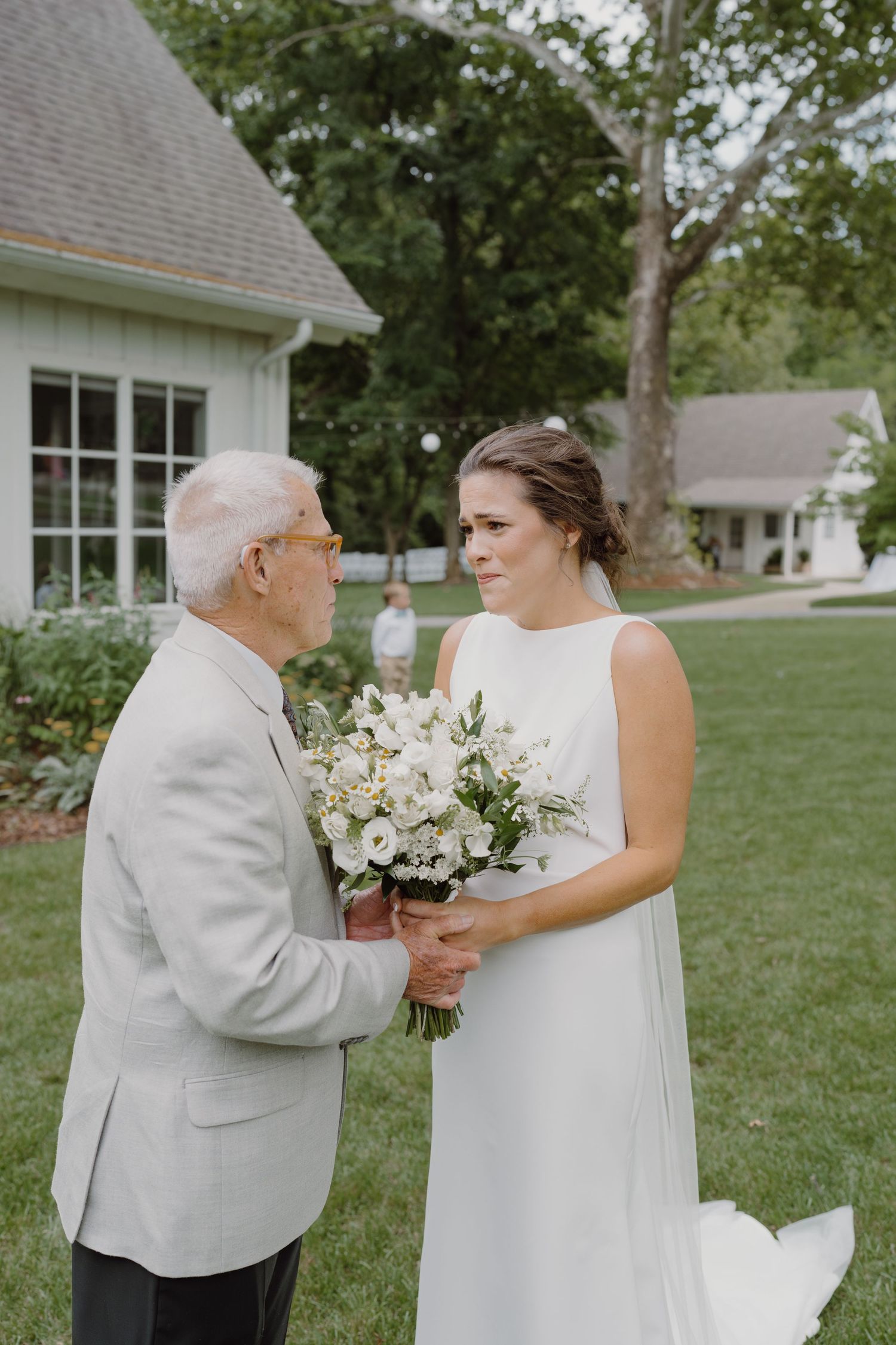 A touching wedding moment shared between two people with white flowers on a green lawn.