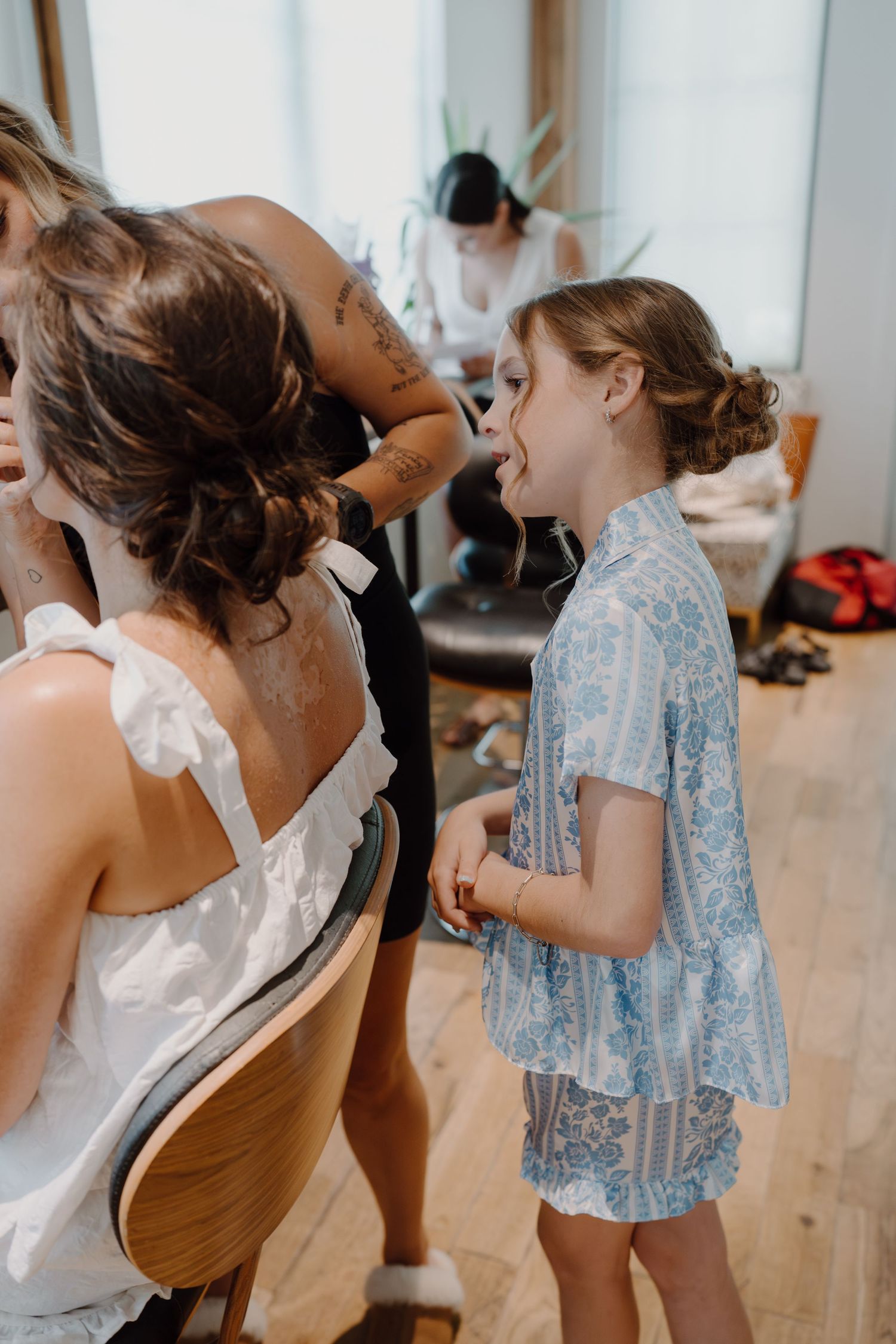 Wedding preparation scene with people in light blue and white dresses.