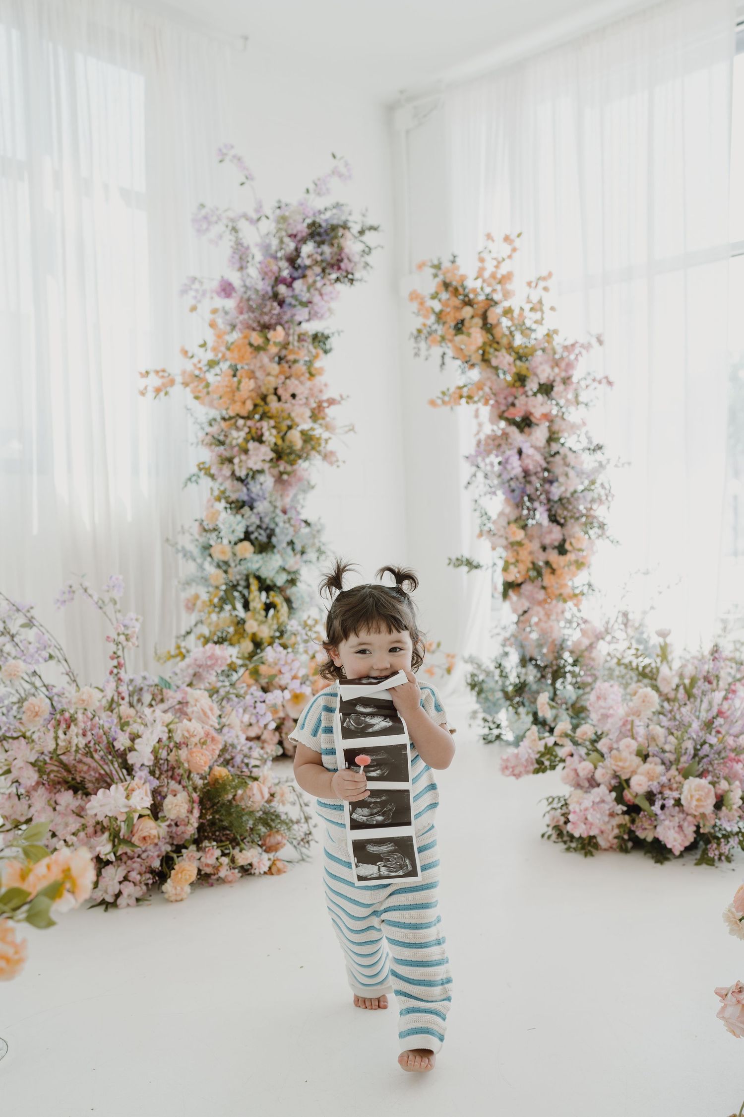 Happy expressions captured in bright studio with romantic floral backdrop.