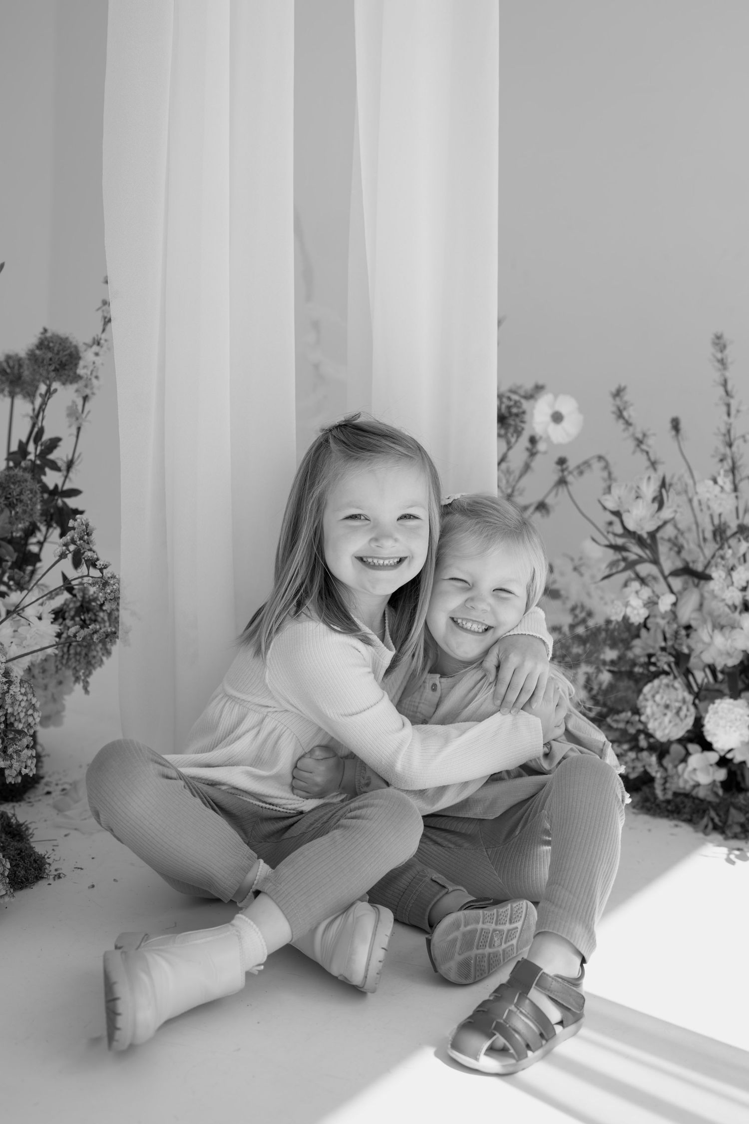 Candid studio portraits showing playful interactions against a white backdrop with flowers.