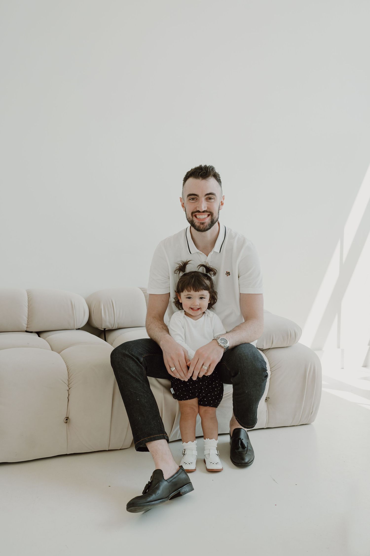 Heartwarming family moment captured in a bright white studio with modern furniture.