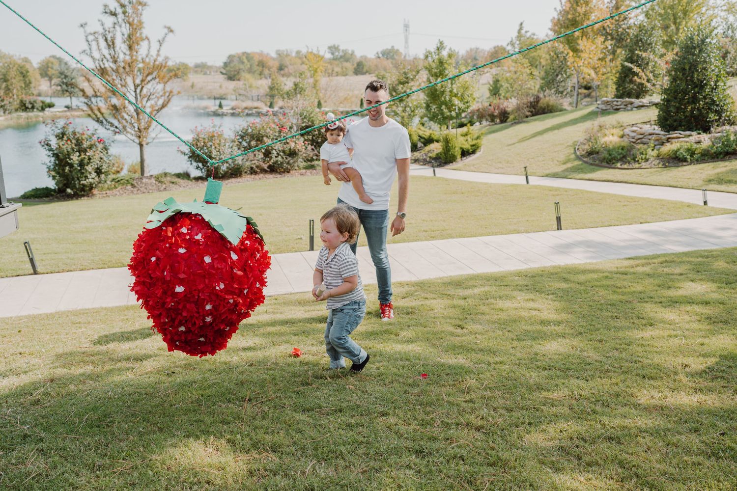 People gather outdoors as a large red heart piñata swings through the air.