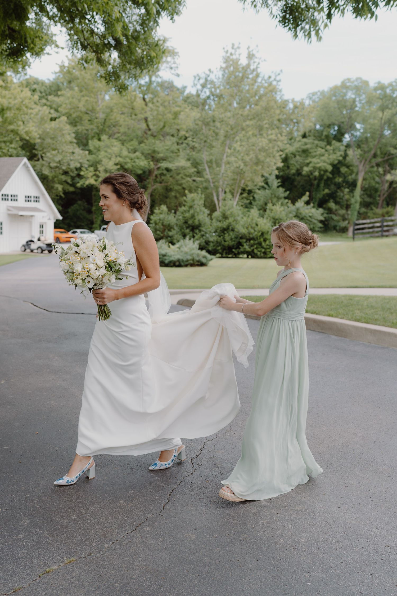 Bridesmaids in mint green dresses playfully pose on a parking lot.