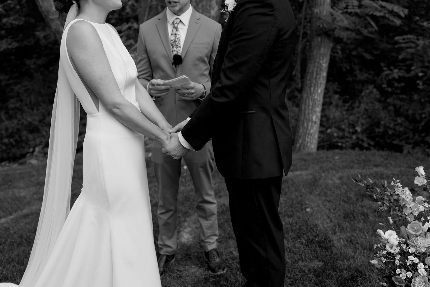 A black and white wedding ceremony photo captured in an outdoor garden setting.