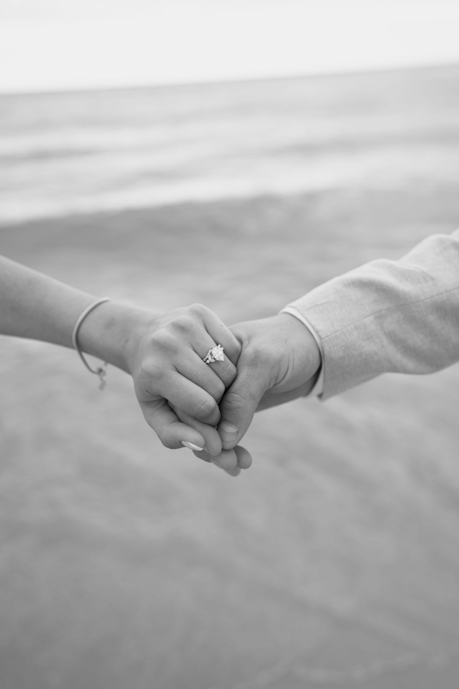 Close-up black and white image of hands holding together against a blurred background.