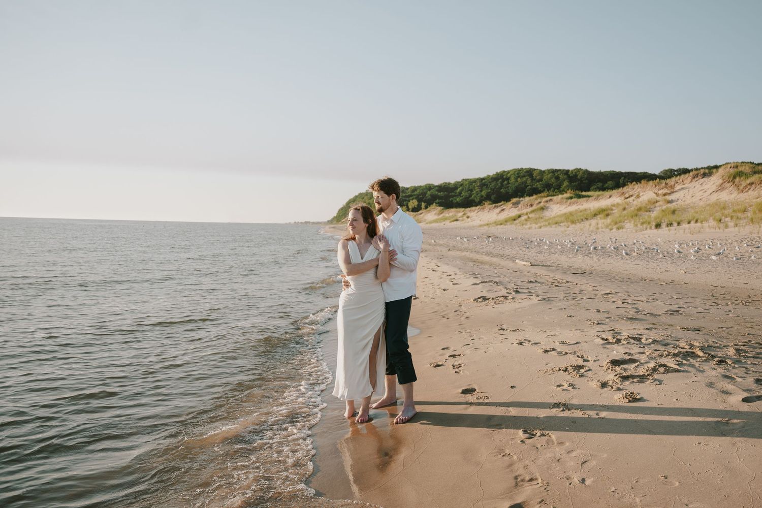 A couple enjoys a romantic moment on a scenic beach with cliffs and ocean views.