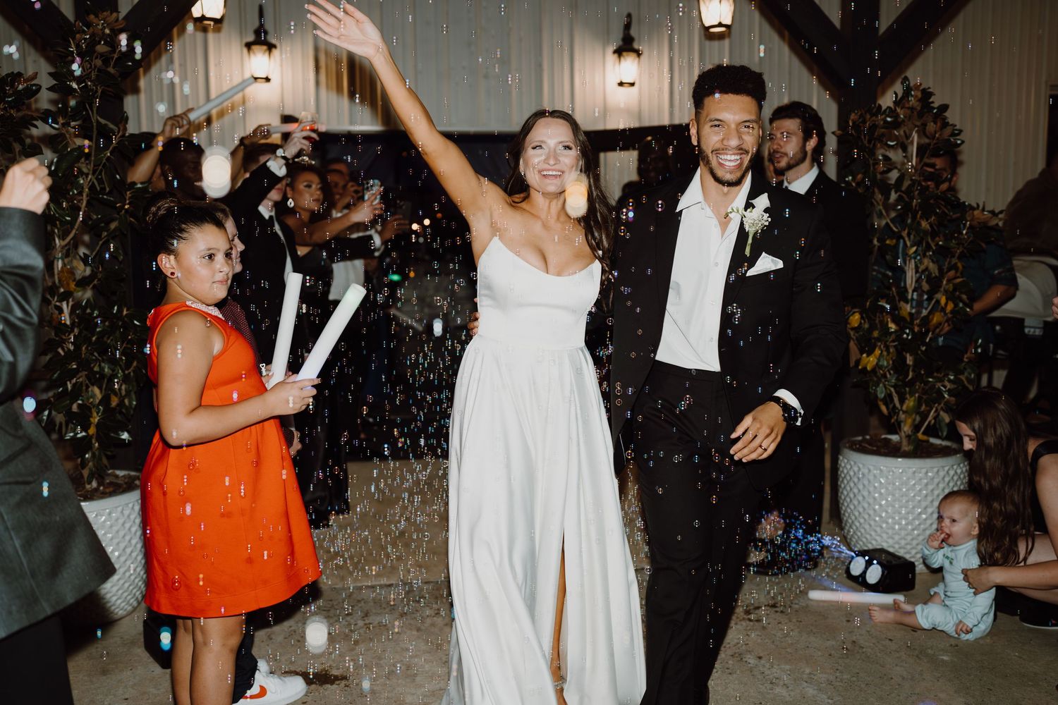 Newlyweds celebrate with joyful dance moves at their wedding reception while confetti falls around them.