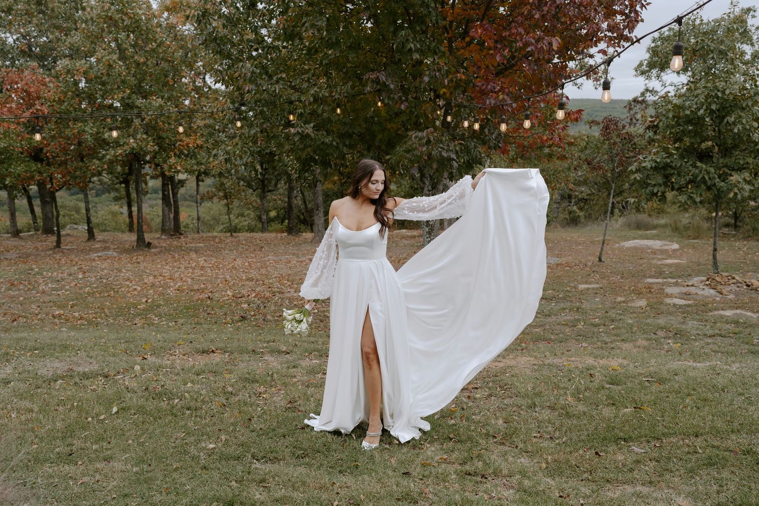 Flowing white wedding dresses captured in motion against autumn trees and grass.
