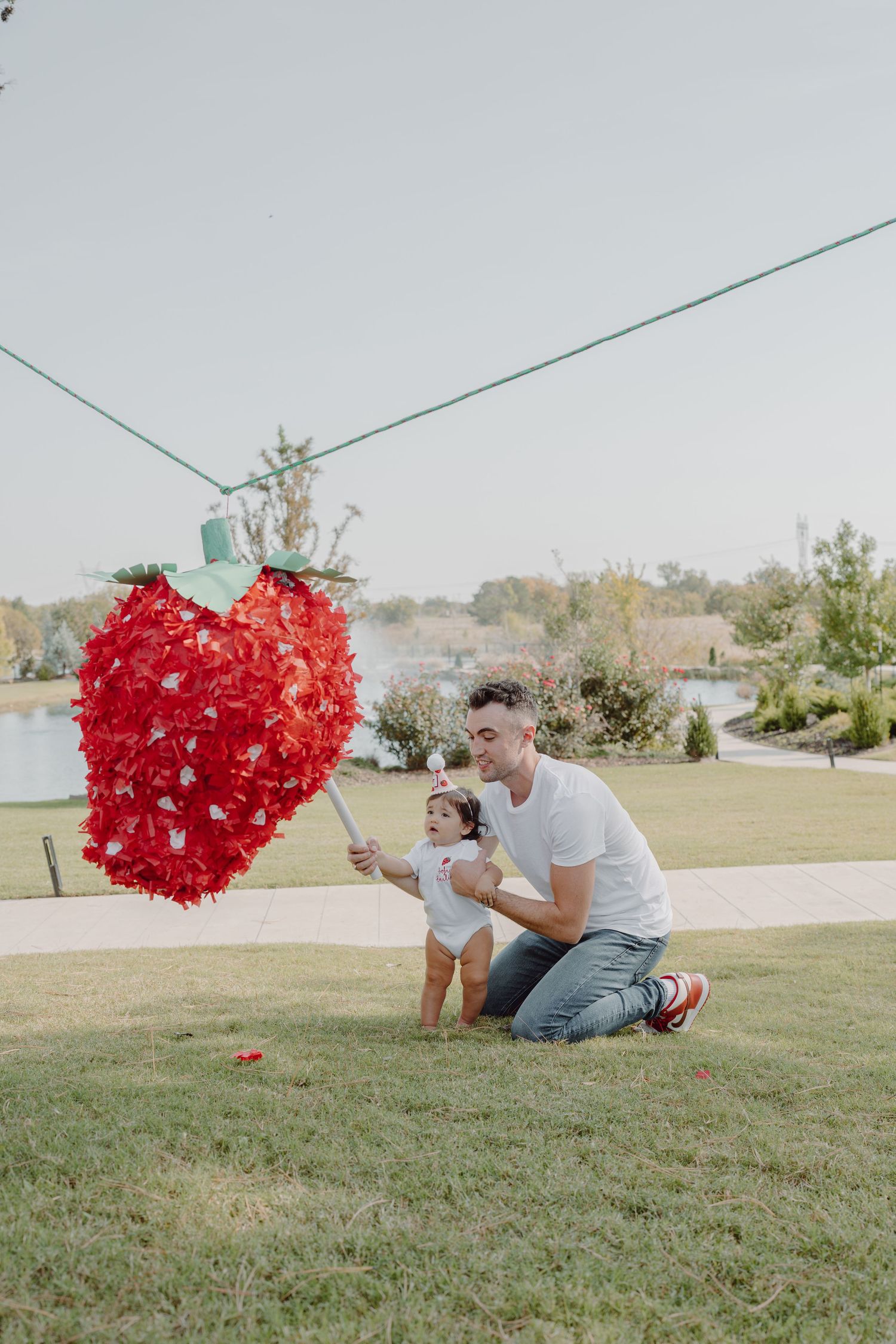 A bright red heart-shaped object swings through the air over a grassy hillside.