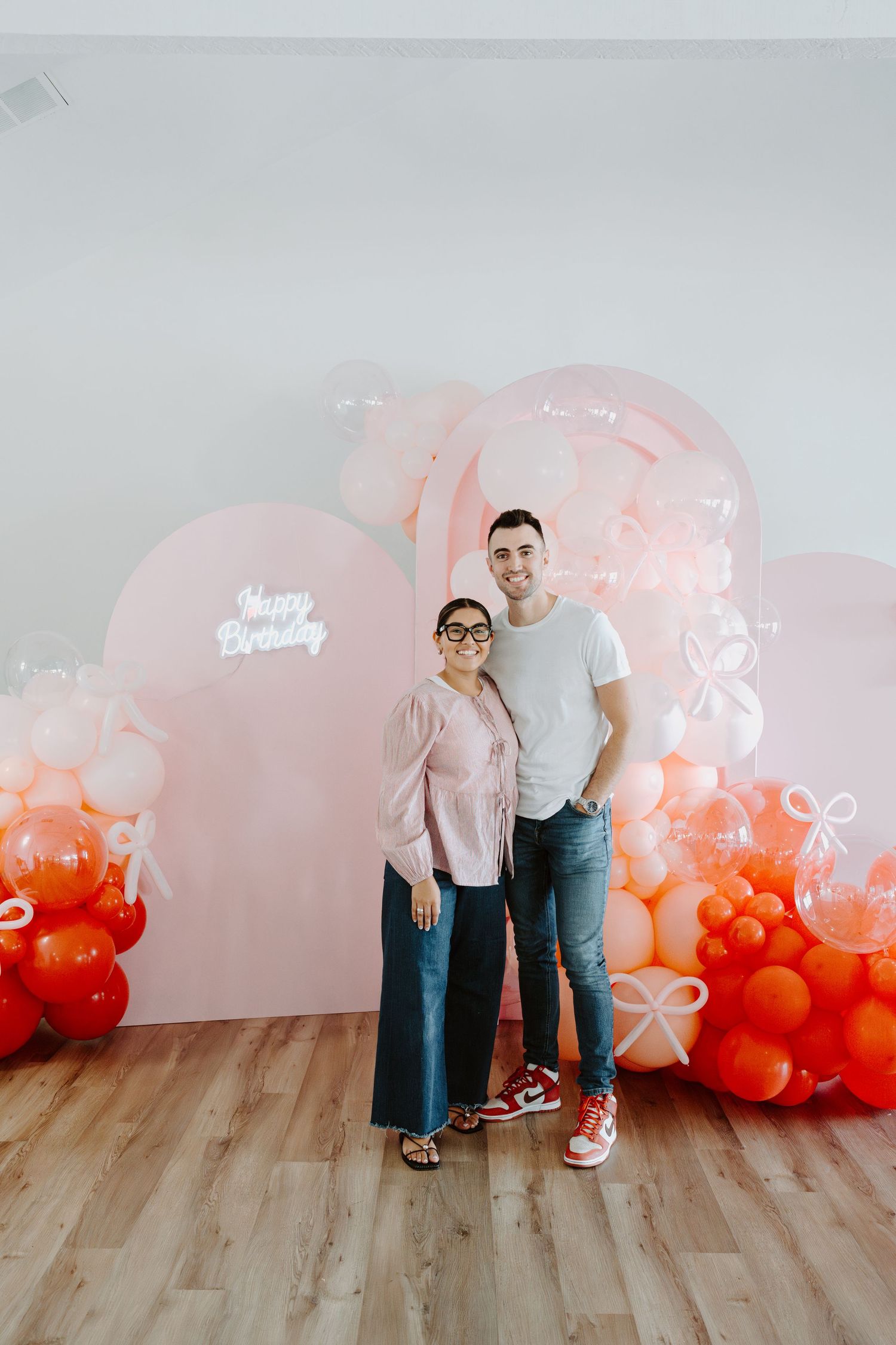 Indoor celebration setup with ombre balloon display ranging from pink to orange.