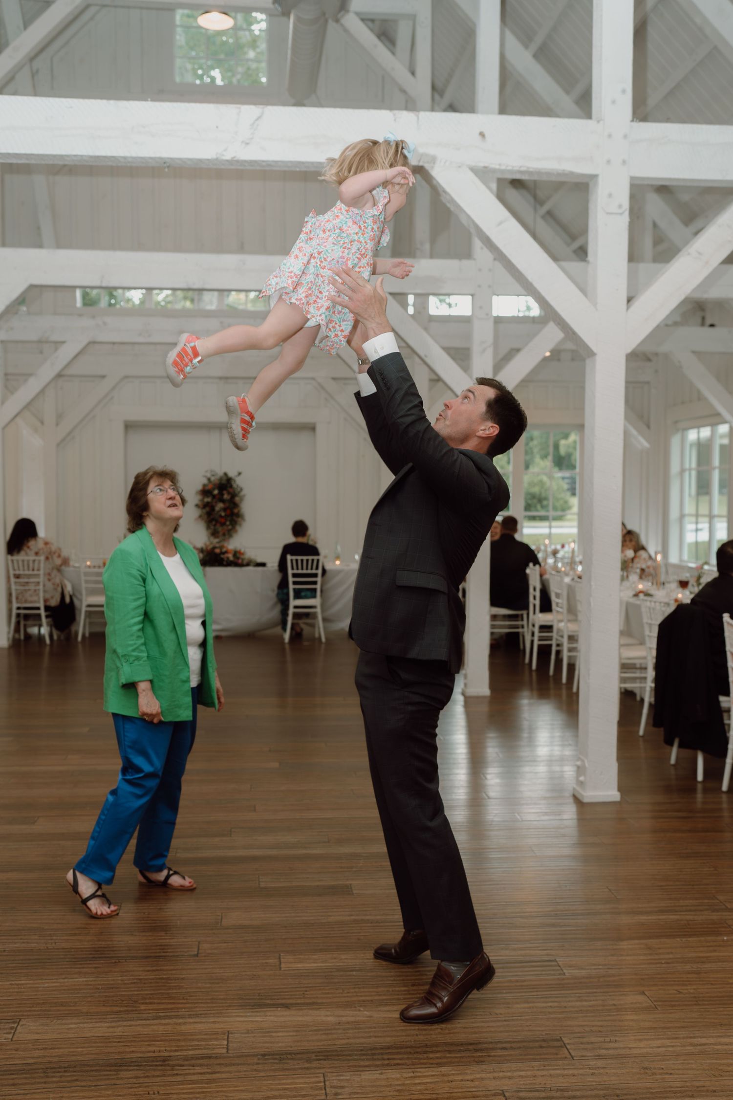 Dancing and celebration on wooden floors in a bright white reception hall.