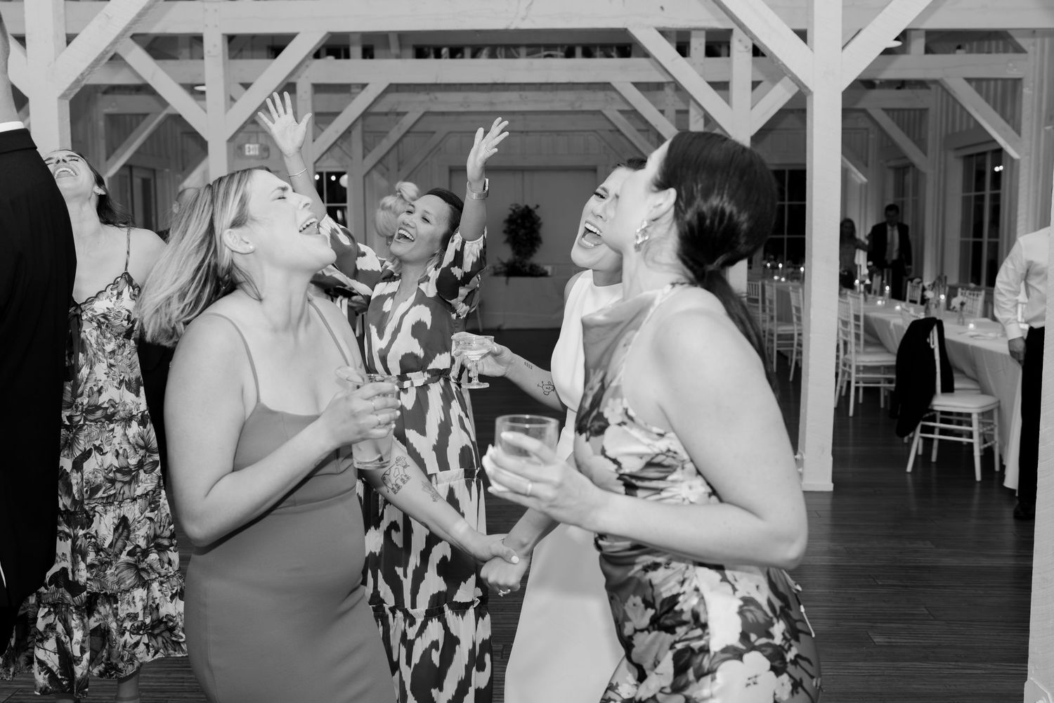Wedding guests celebrate on the dance floor of a rustic barn venue.