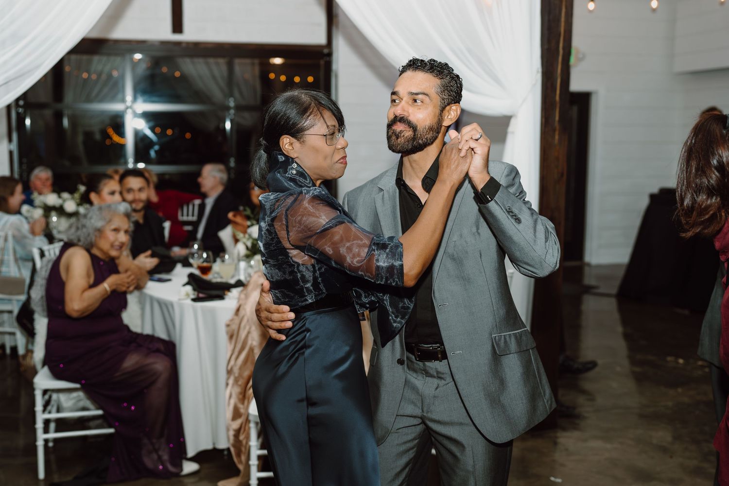Wedding guests dancing together on the reception dance floor with elegant lighting and decor.