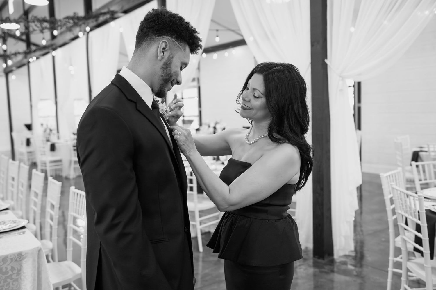 A couple shares a tender moment in a beautifully decorated white reception venue.