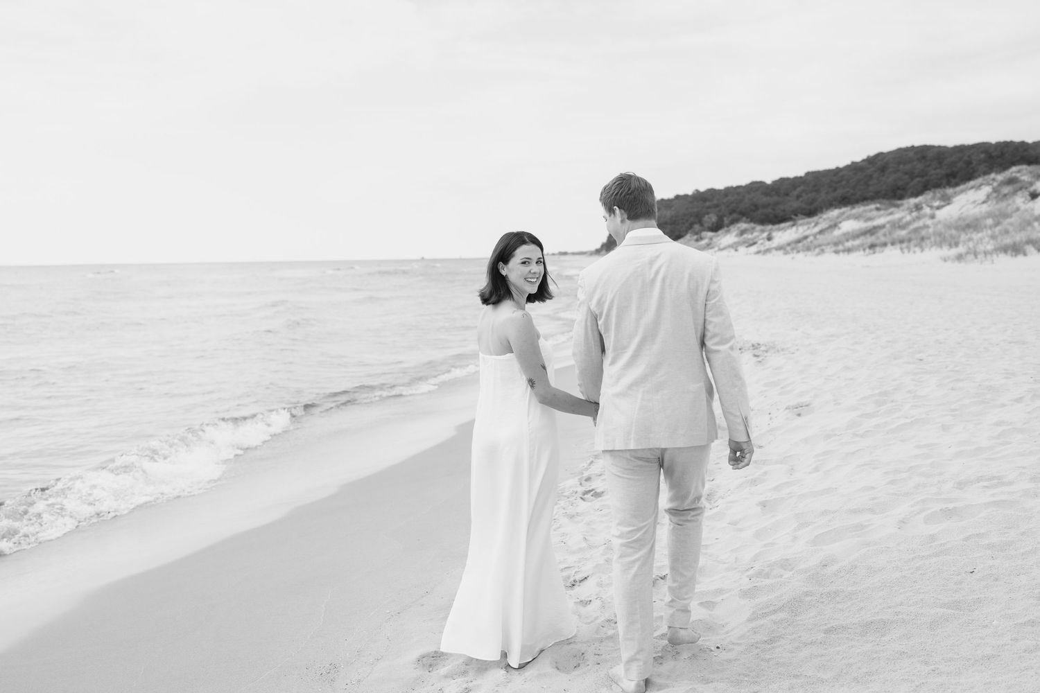 A couple takes a romantic stroll along a serene beach with gentle waves.