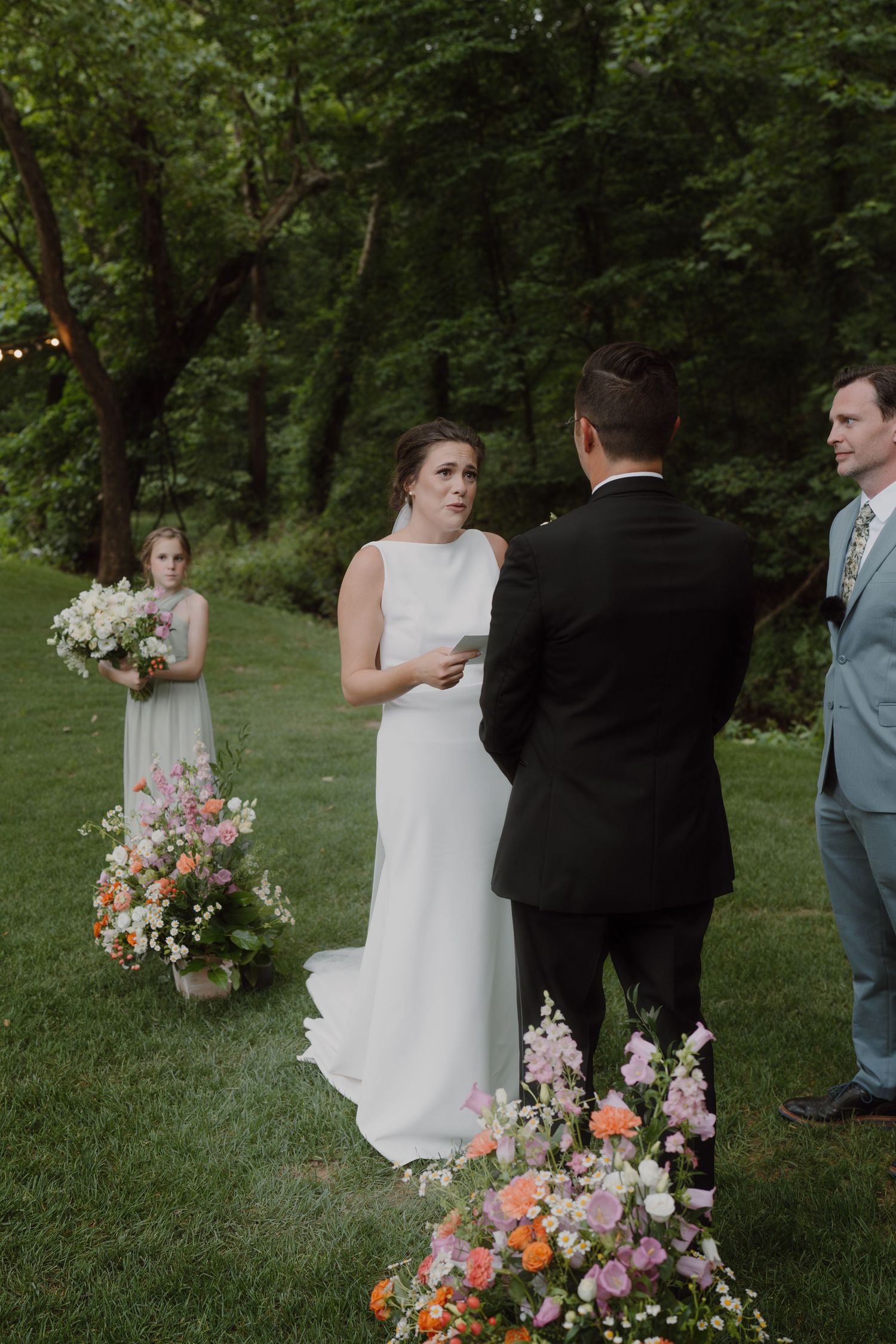 Wedding ceremony in progress with colorful floral arrangements in a garden setting.