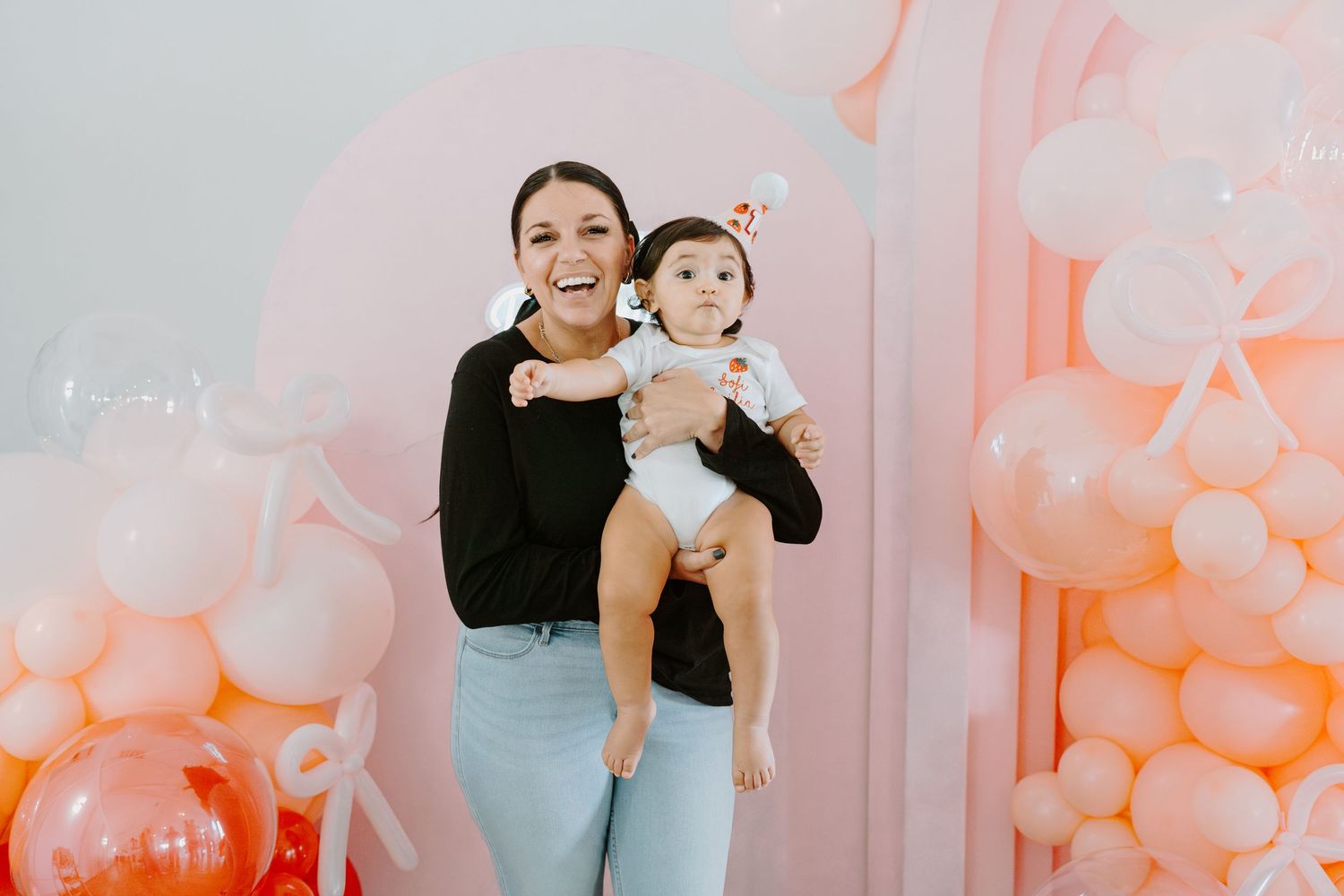 Family photoshoot in a studio with pink balloon decorations and white walls.