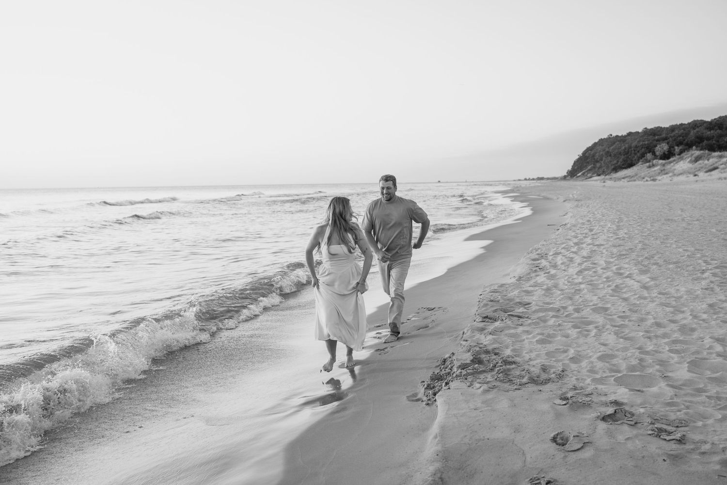 Wide angle shots of a couple walking together on a peaceful beach with rolling waves.