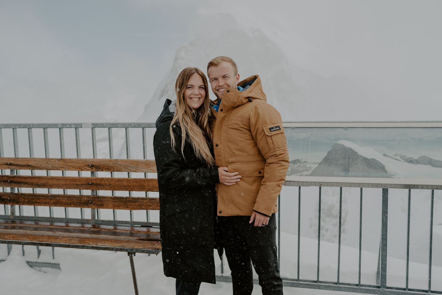 Couple enjoying mountain views from observation deck in winter.