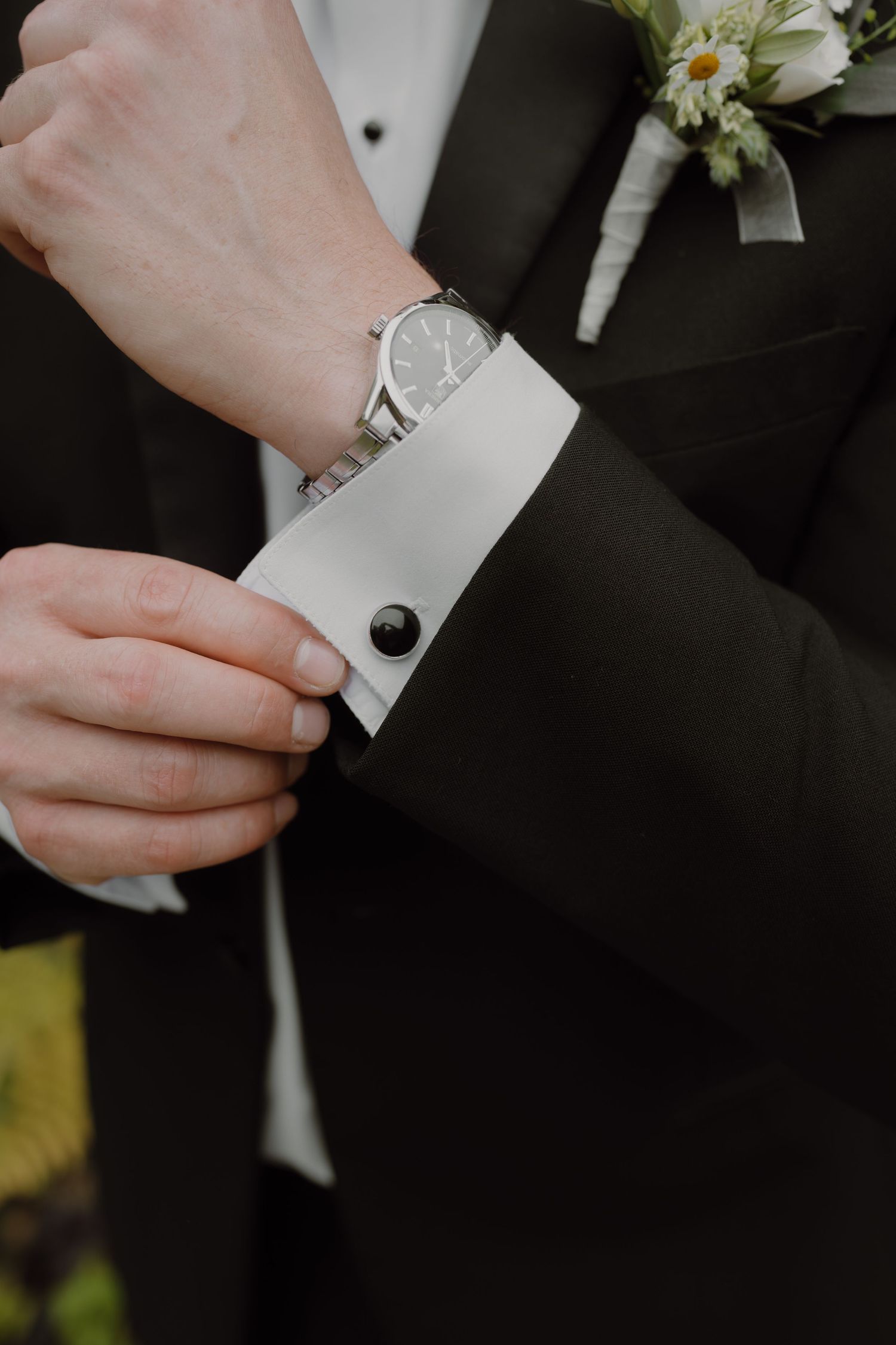 Close-up of hands adjusting white shirt cuffs with cufflinks.