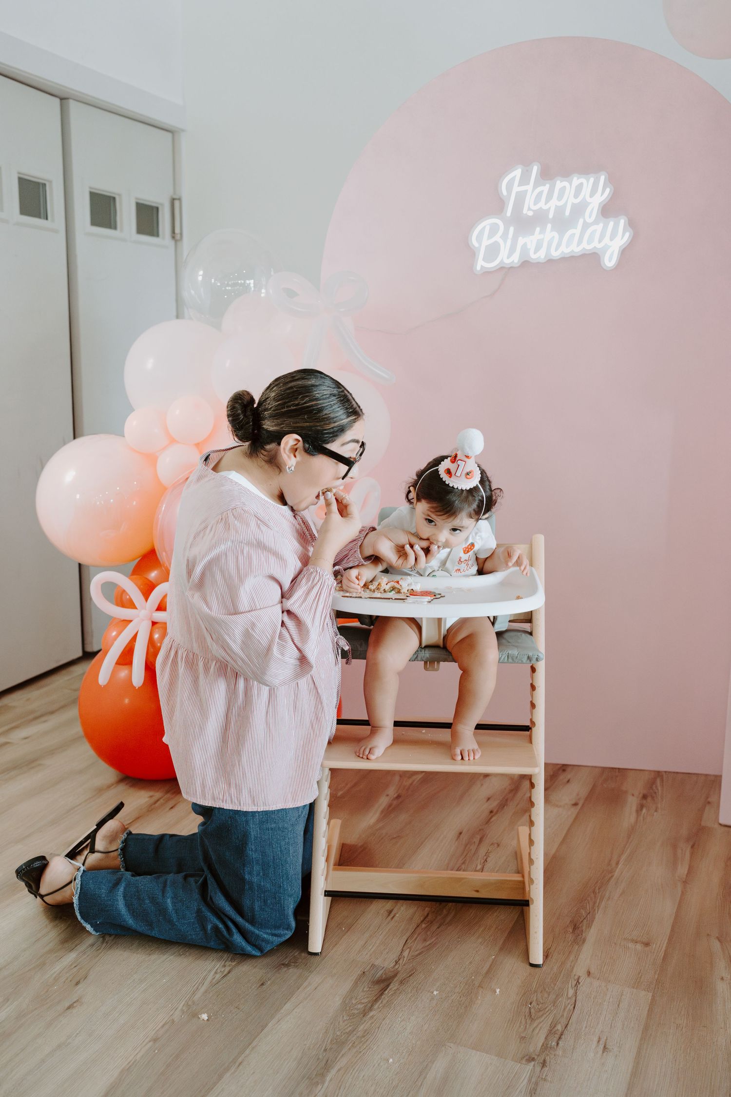 Pink-themed birthday setup with balloons and wooden flooring.
