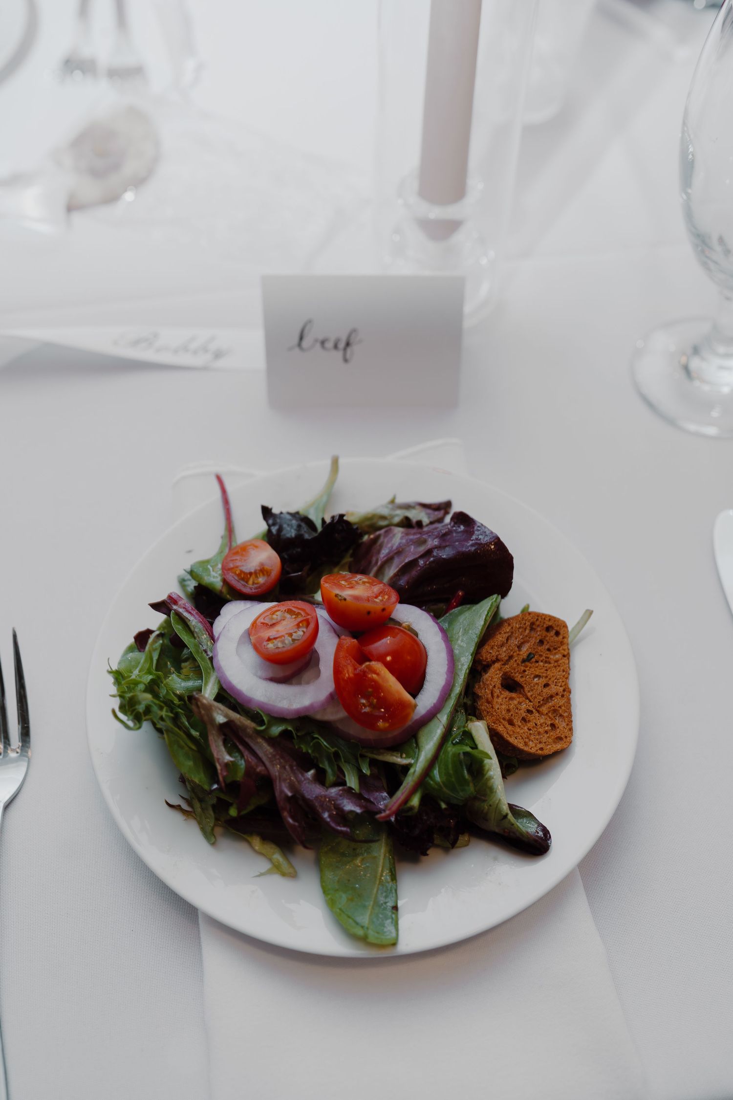 Fresh garden salad with cherry tomatoes and mixed greens plated on white dinnerware.