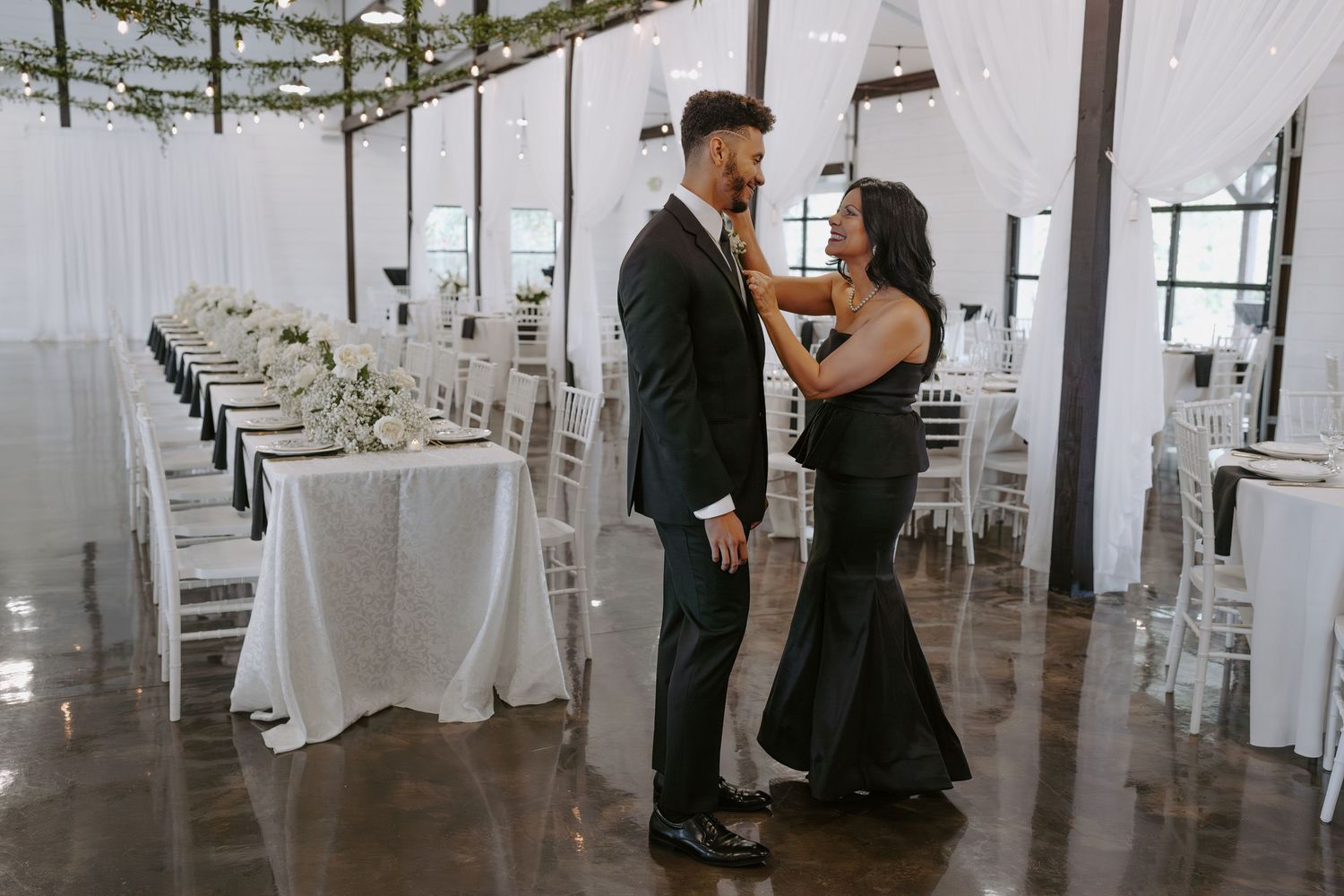 An elegant white reception hall with draped walls and tables set for a formal event.