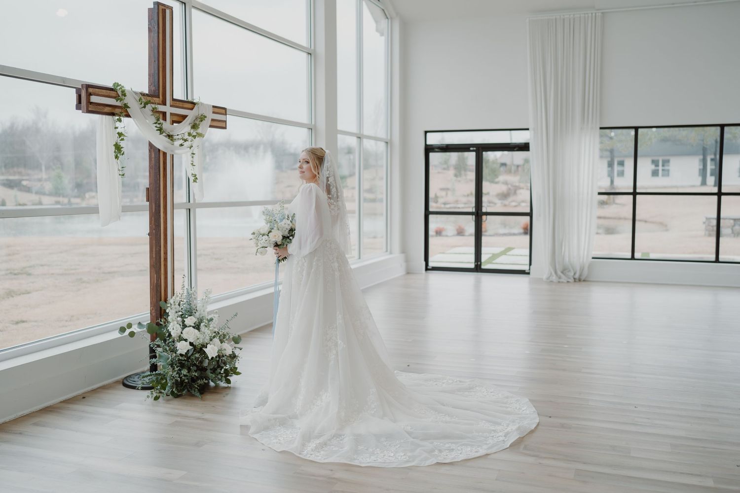 Elegant wedding chapel interior with large cross and floral arrangements by window.