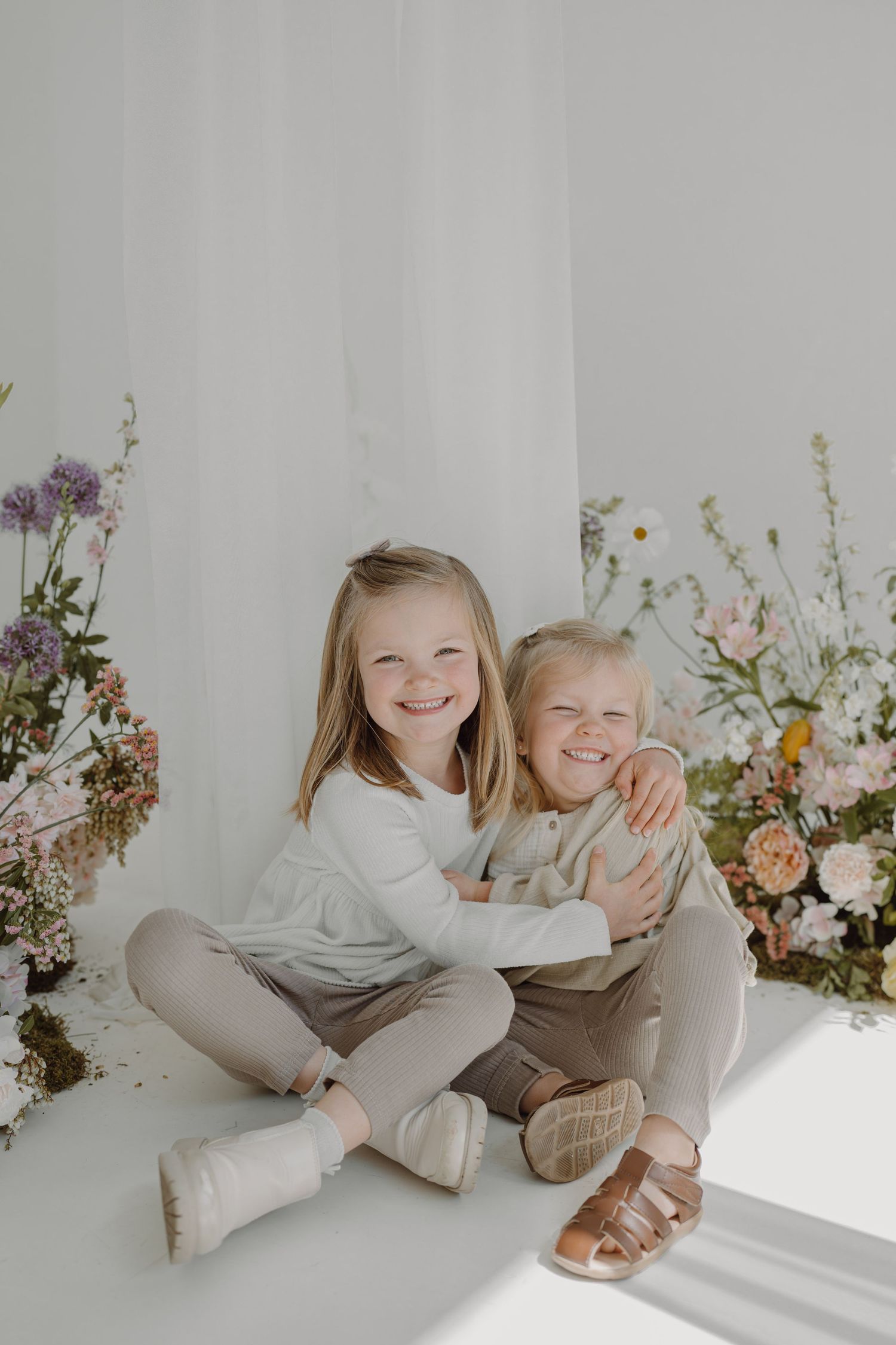 Light-filled studio session capturing sweet moments between two people with spring flowers.