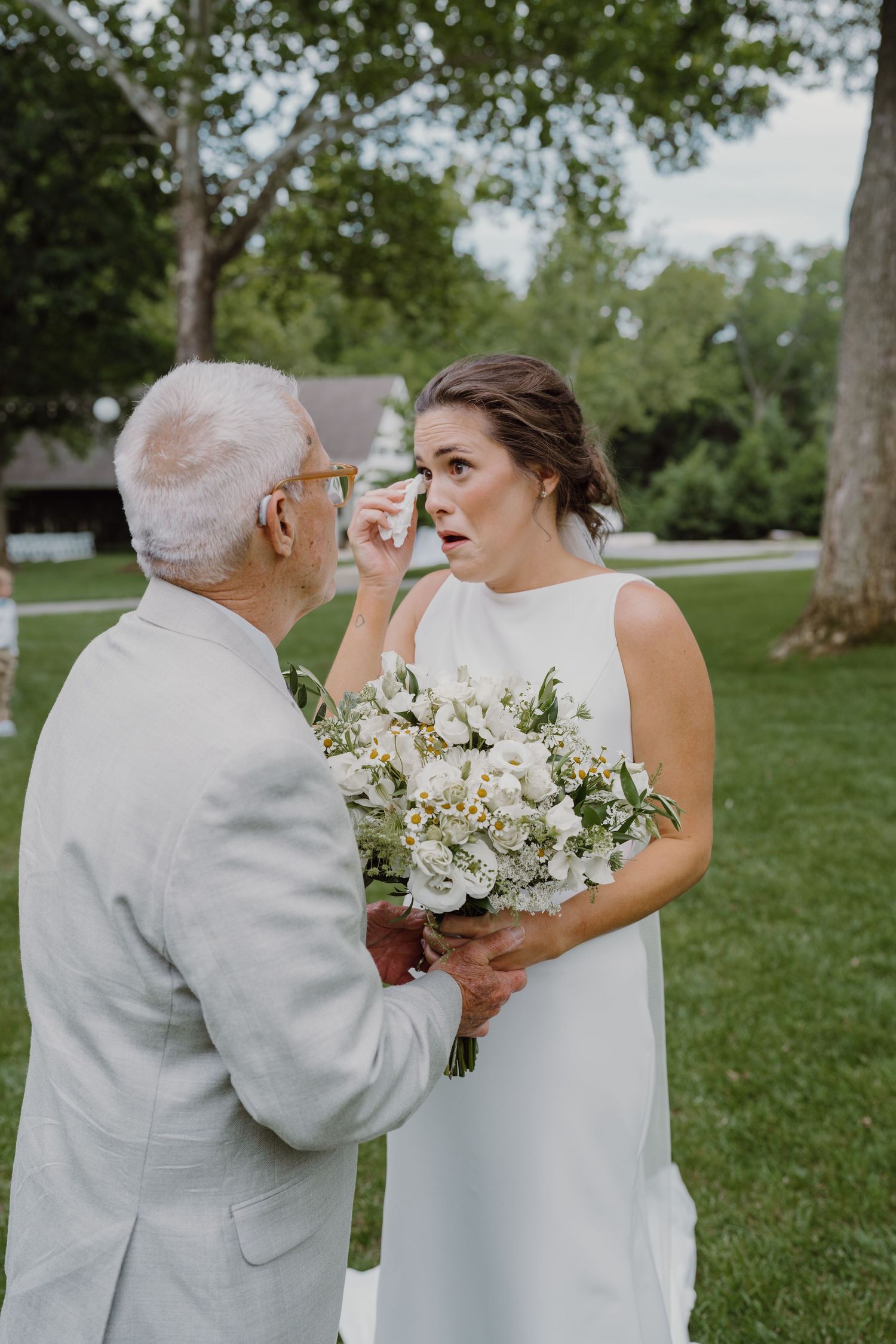 Two people share an intimate moment during a wedding first look with white floral bouquet.