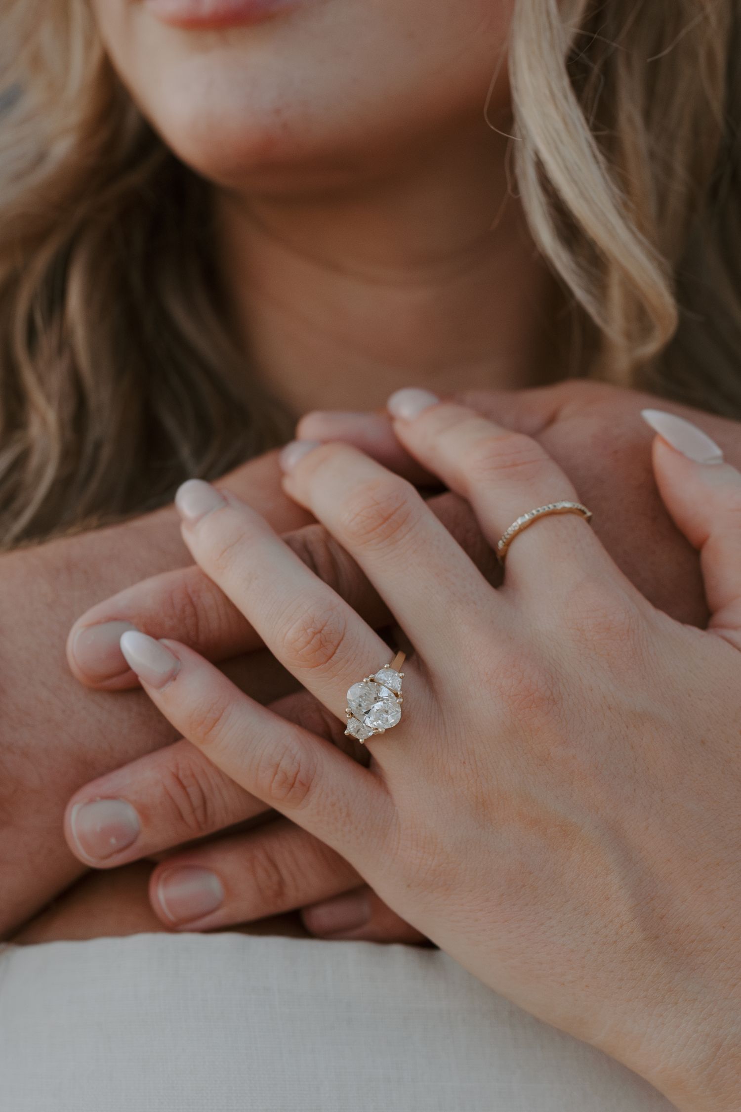 Close-up shot of hands displaying an engagement ring with sparkling diamond.