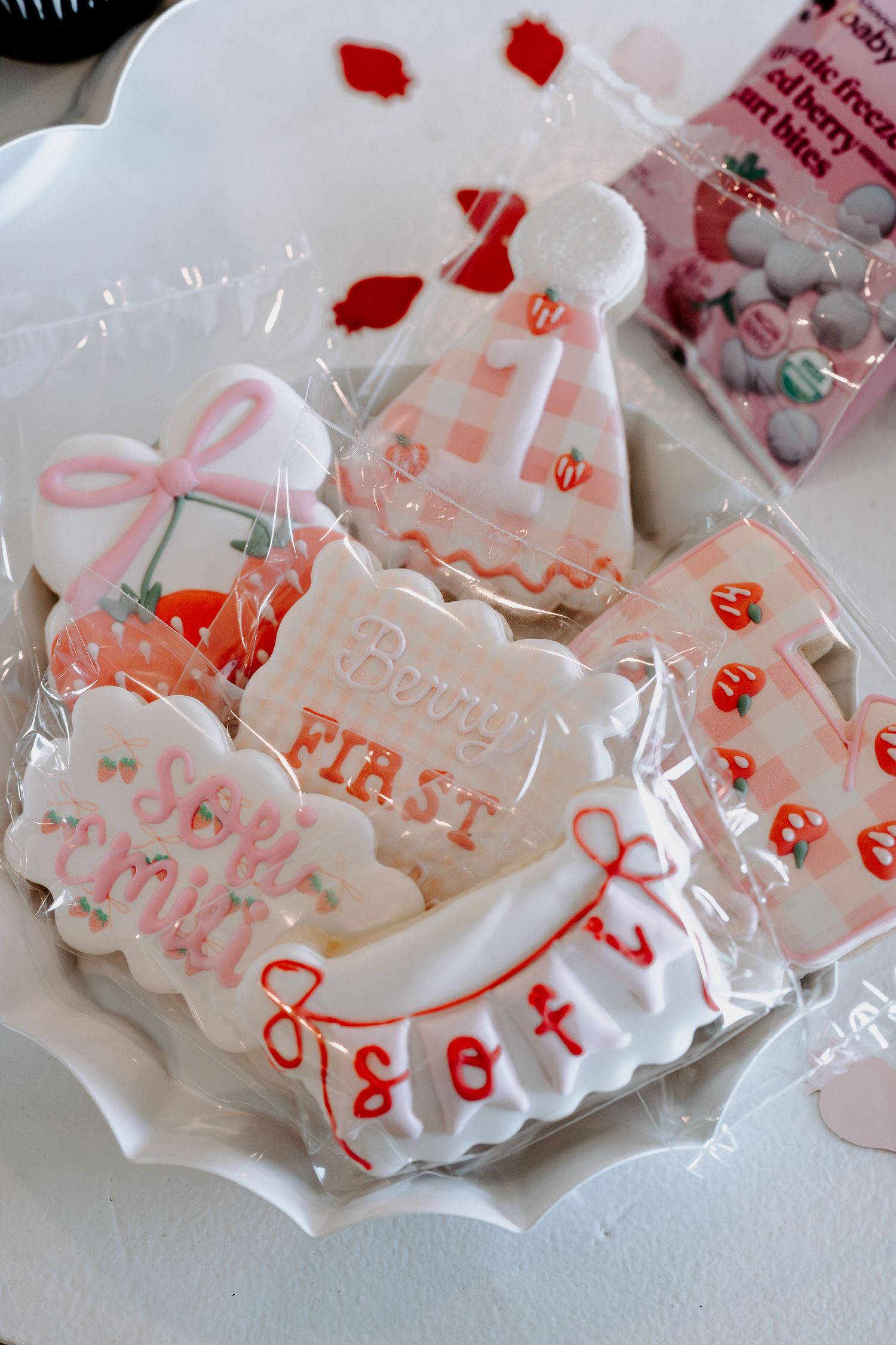 Party favor bags with pink lettering and strawberry designs wrapped in clear protective packaging.
