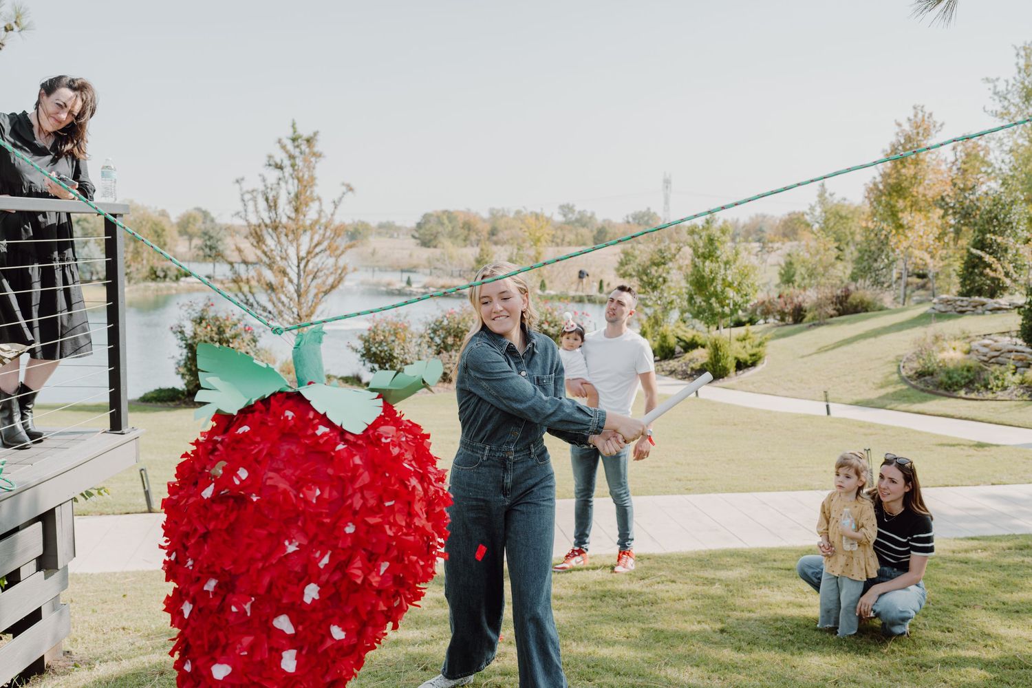 A red heart-shaped piñata moves through the air during an outdoor celebration.