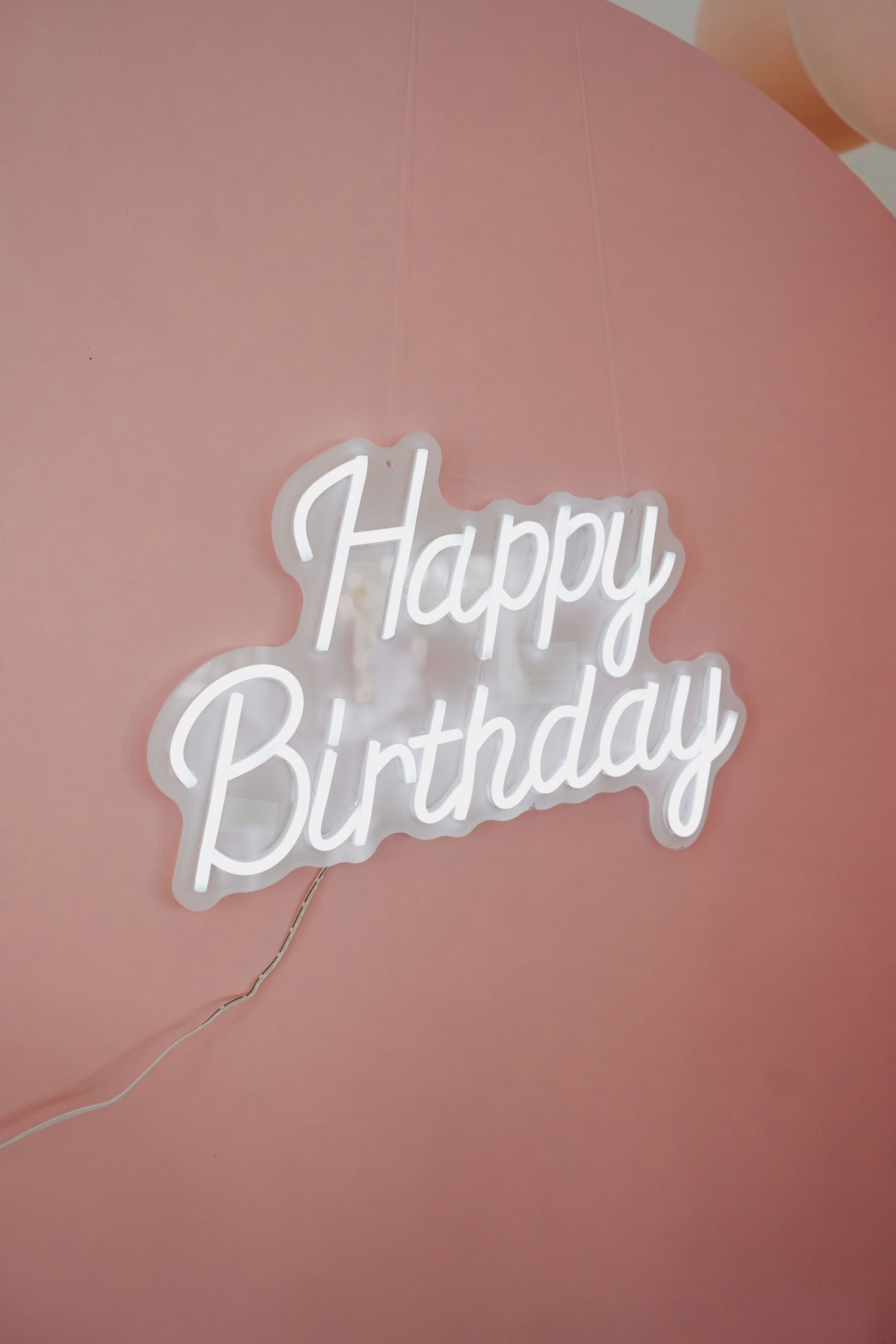 White 'Happy Birthday' text mounted on a pink wall.