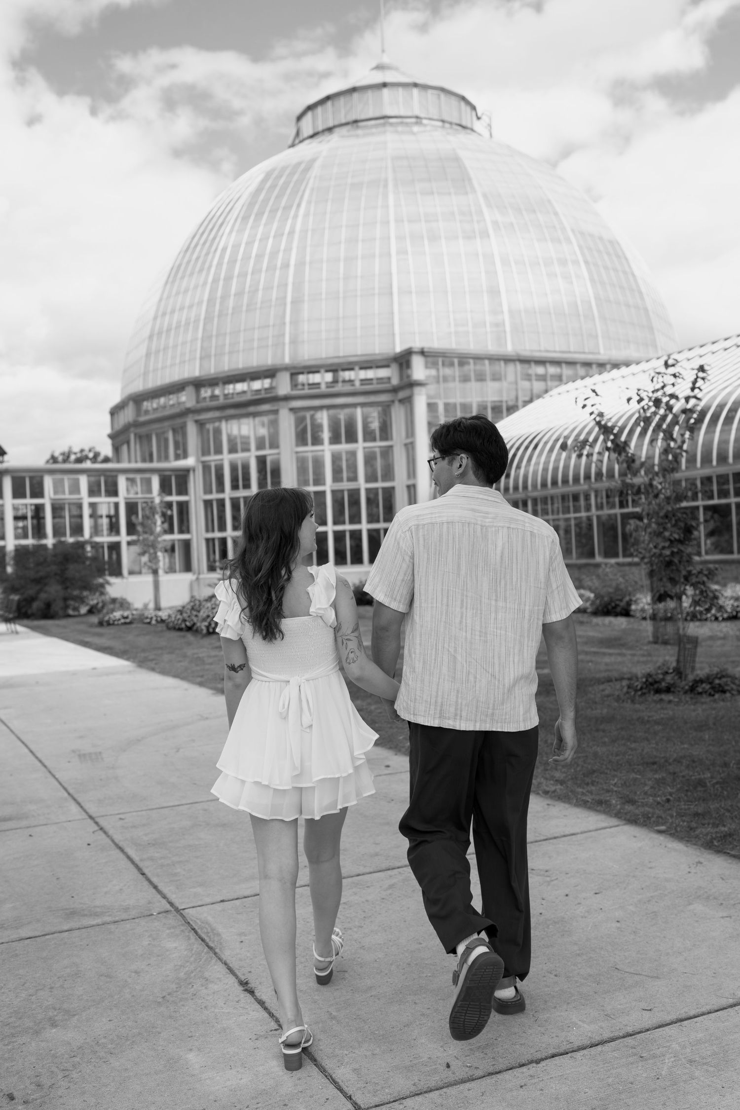 Black and white photo of a couple walking away from a domed greenhouse structure.