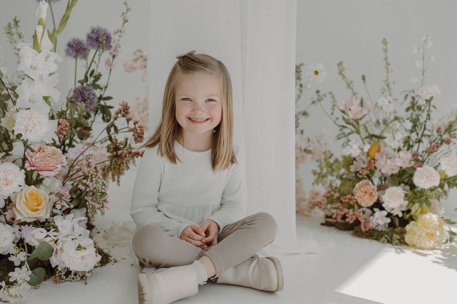 Light-filled studio portrait with romantic floral arrangements of roses and mixed flowers.