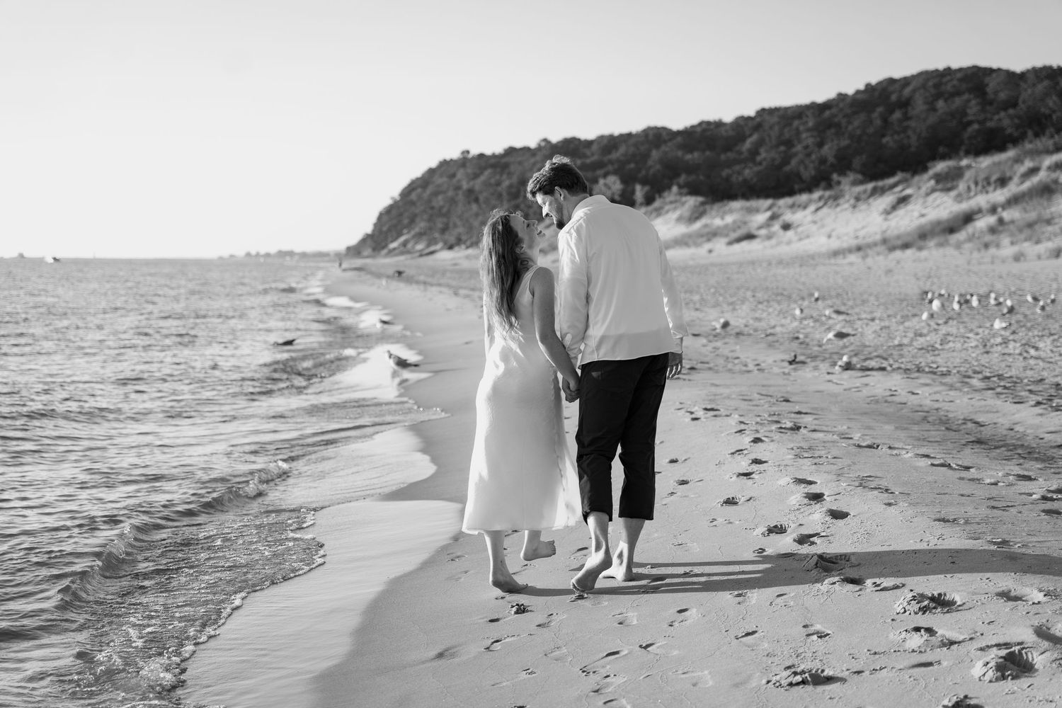 A couple takes a romantic walk along the shoreline of a secluded beach.