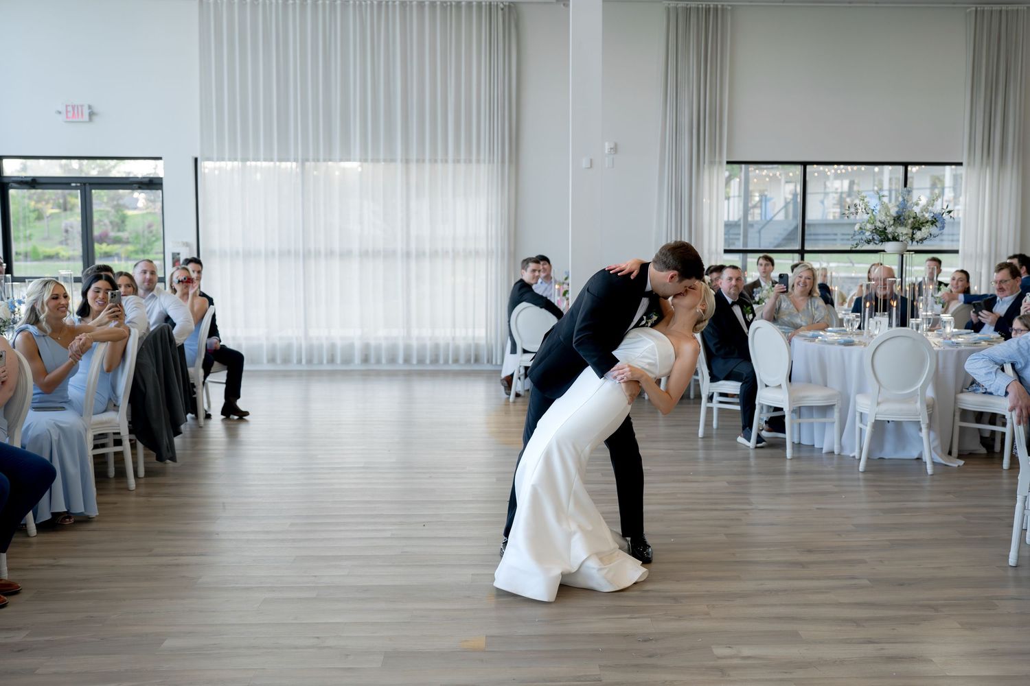 Bride and groom share a romantic dip kiss on the dance floor during their wedding reception.
