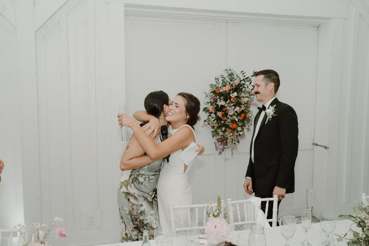 Wedding celebration continues with guests interacting in an elegant white venue.