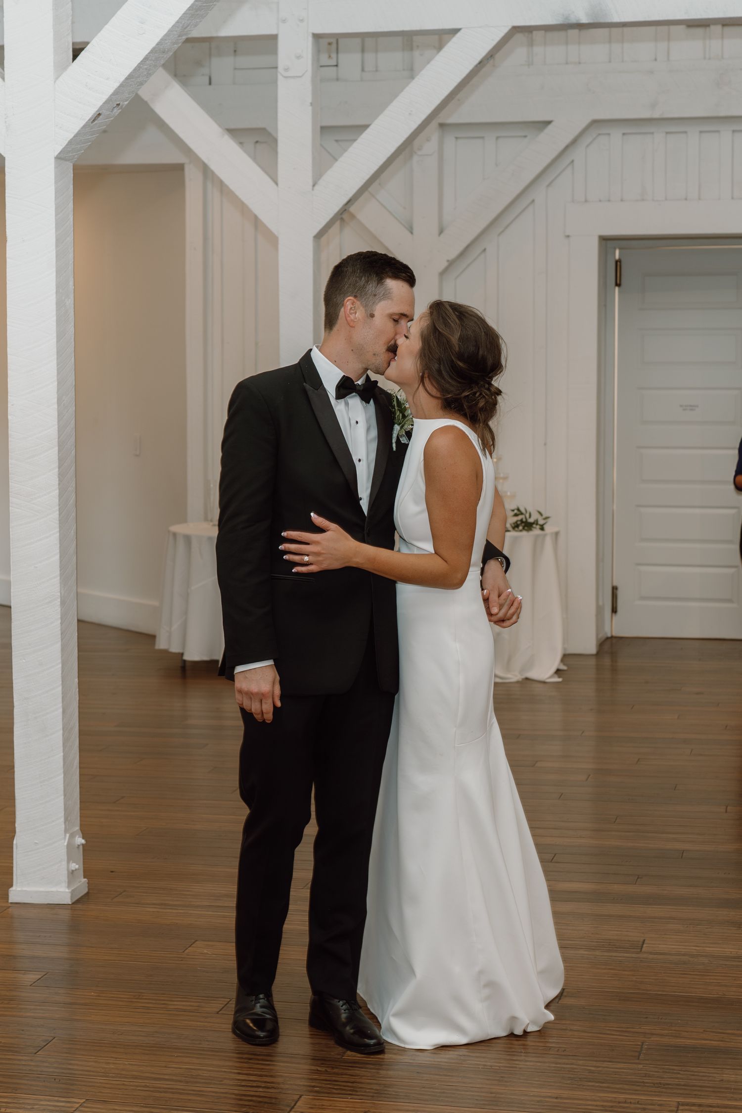 Wedding celebration moments captured in a bright white venue with wooden floors.