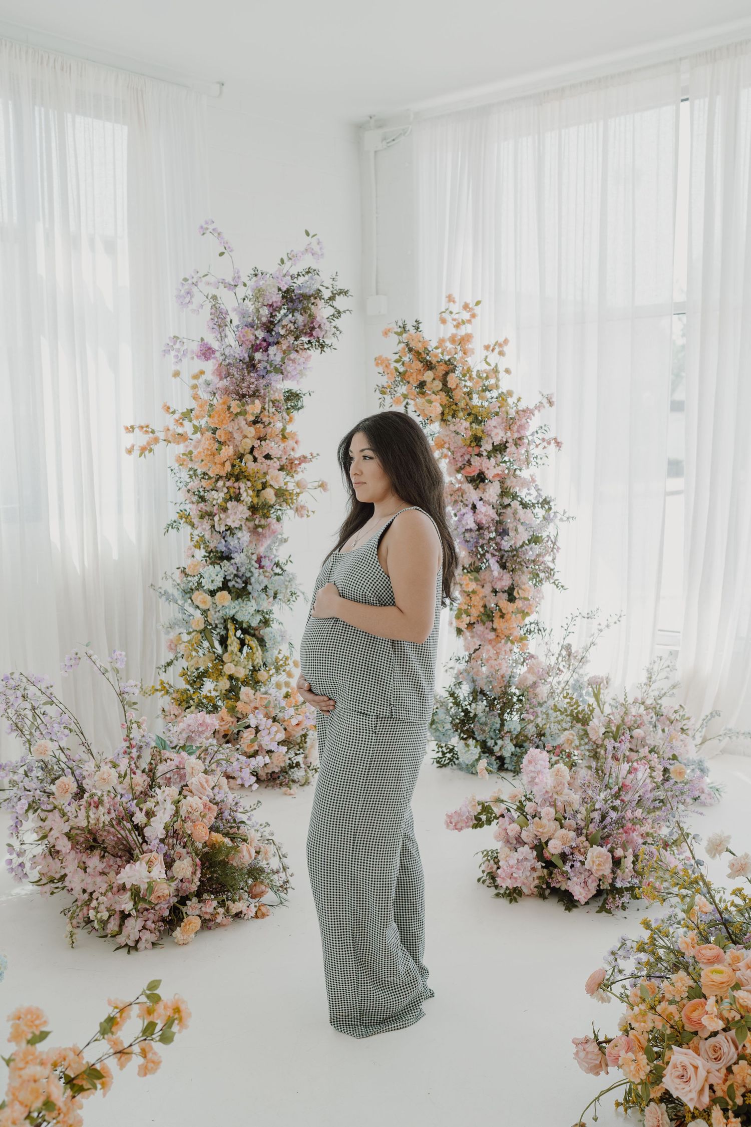 Ethereal maternity session featuring soft lighting and cascading flower installations.