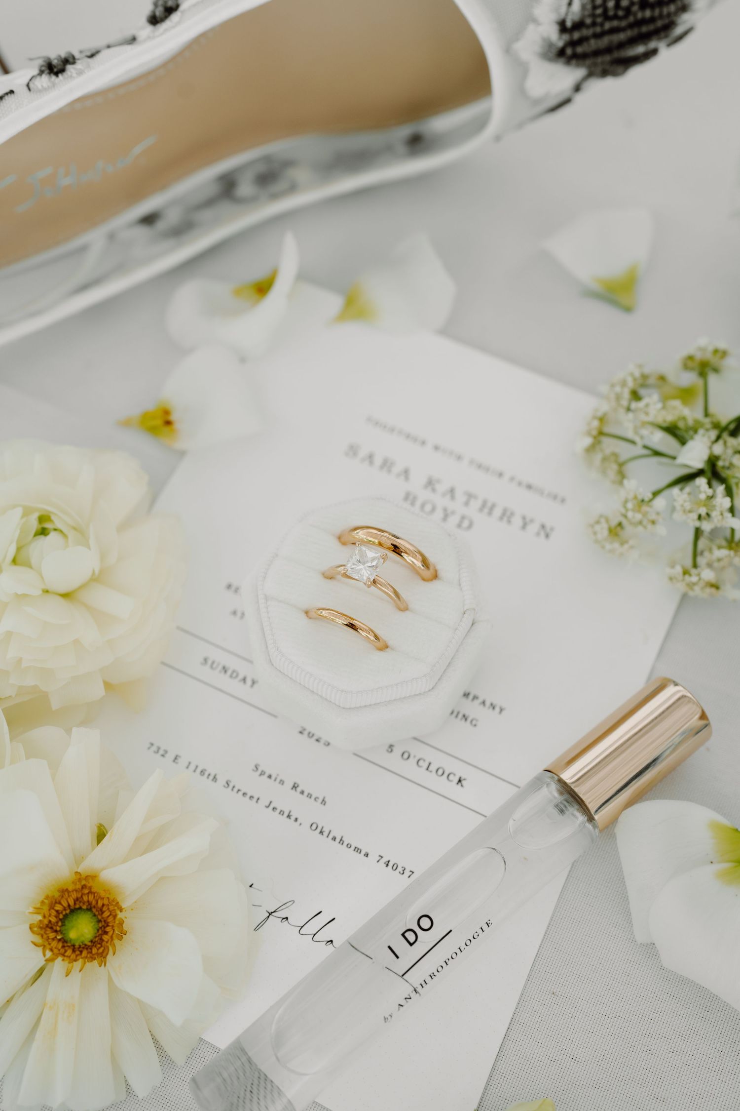 Wedding stationery with gold rings and white florals in minimalist styling.