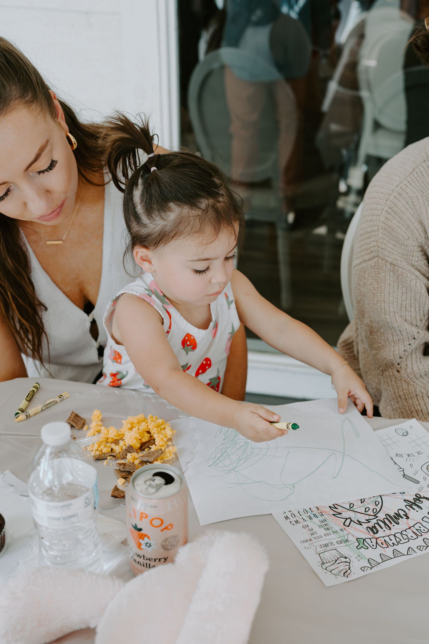 Children coloring and drawing with art supplies at a white table during a creative activity.